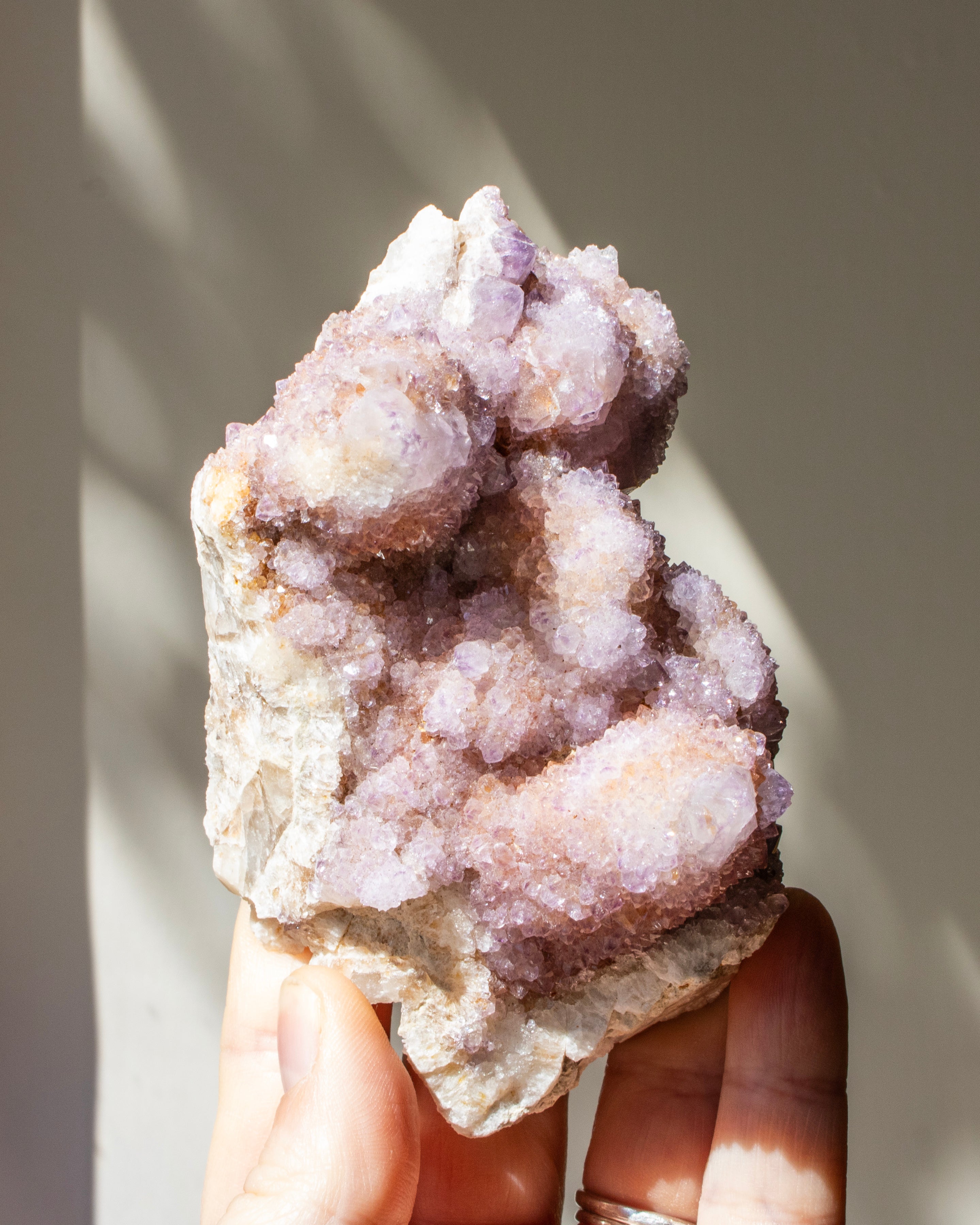 crystal cluster being held against a neutral beige background