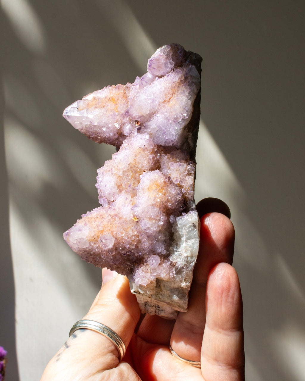 crystal cluster being held against a neutral beige background