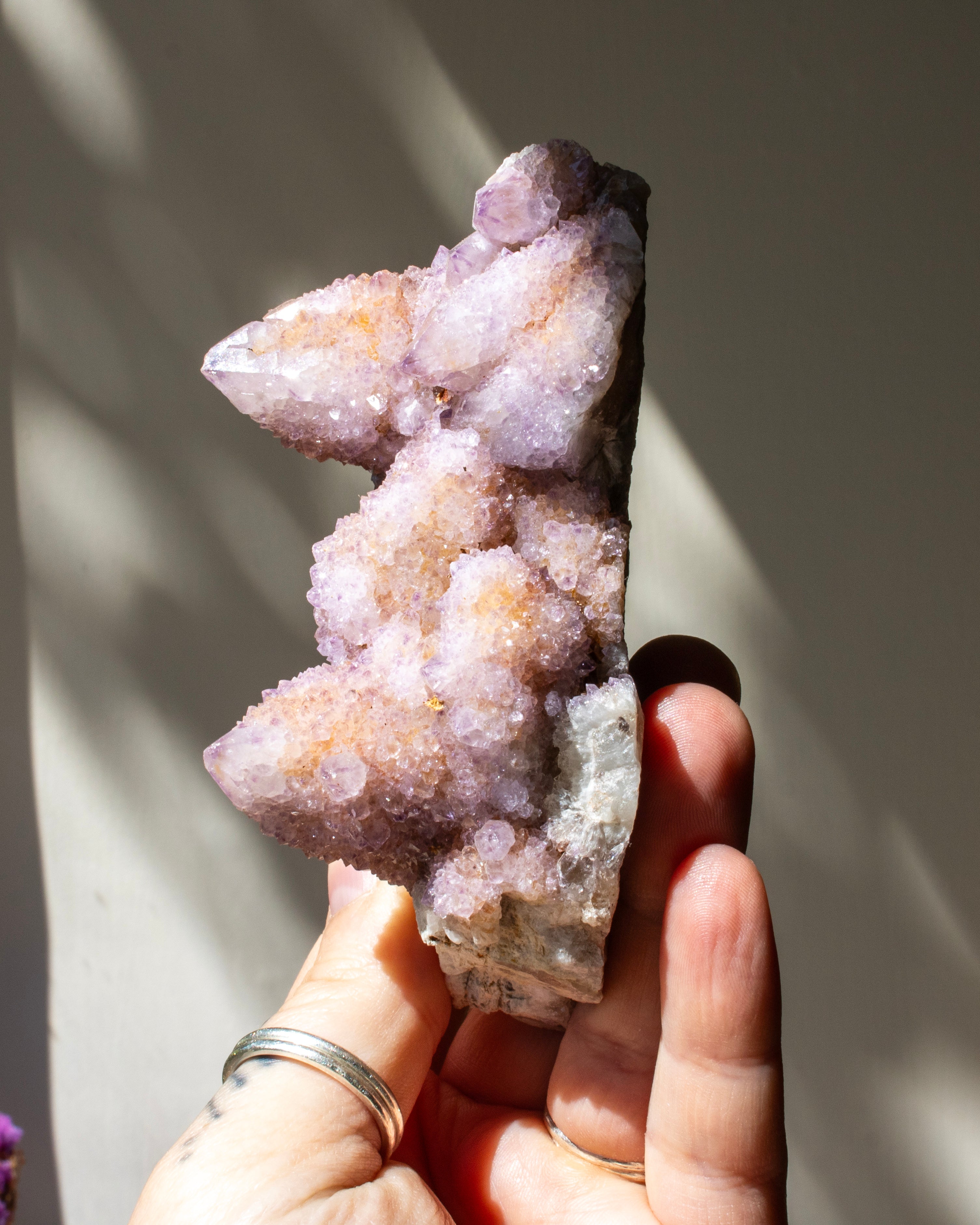 crystal cluster being held against a neutral beige background