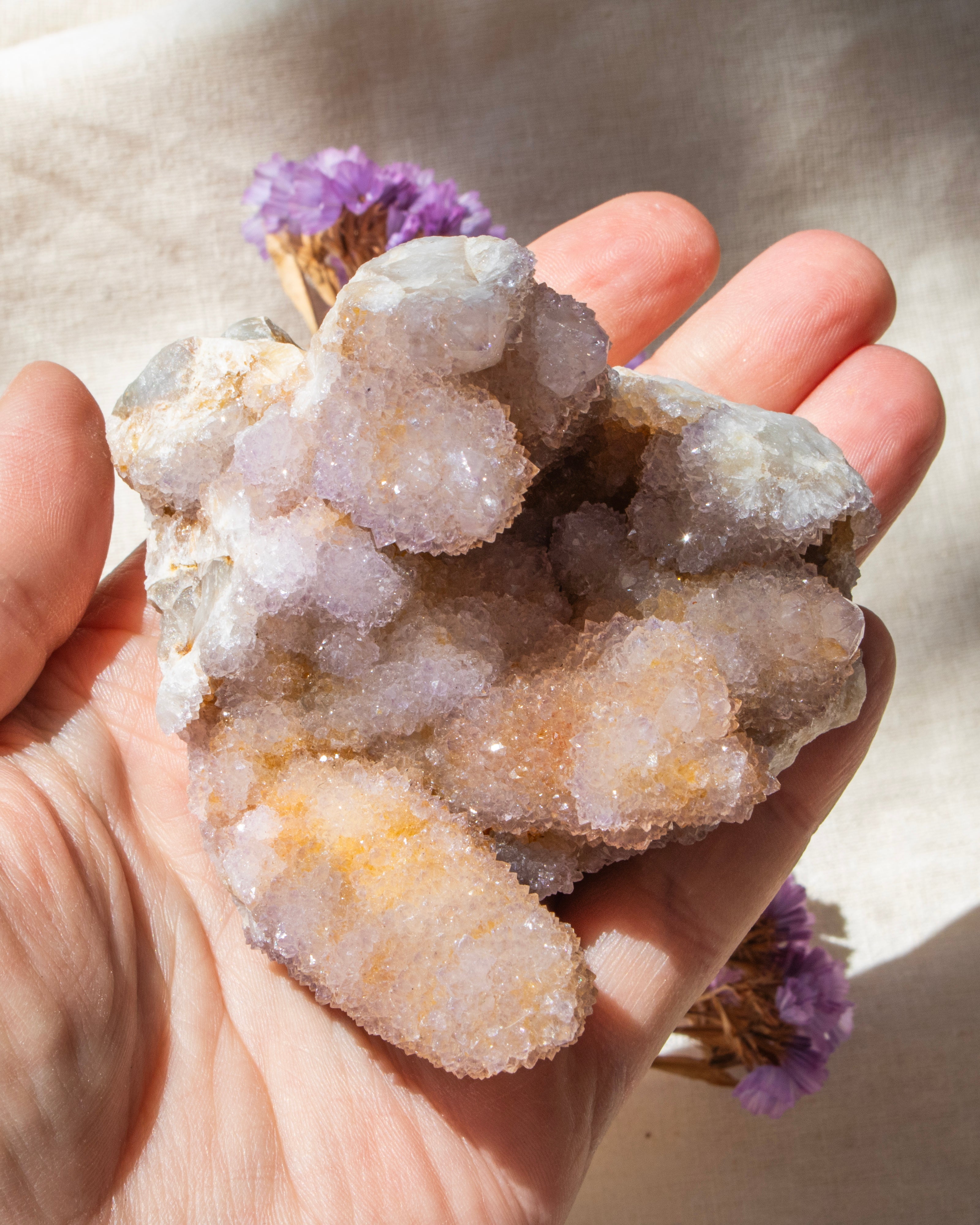 purple crystal cluster being held in a hand with a blurred background