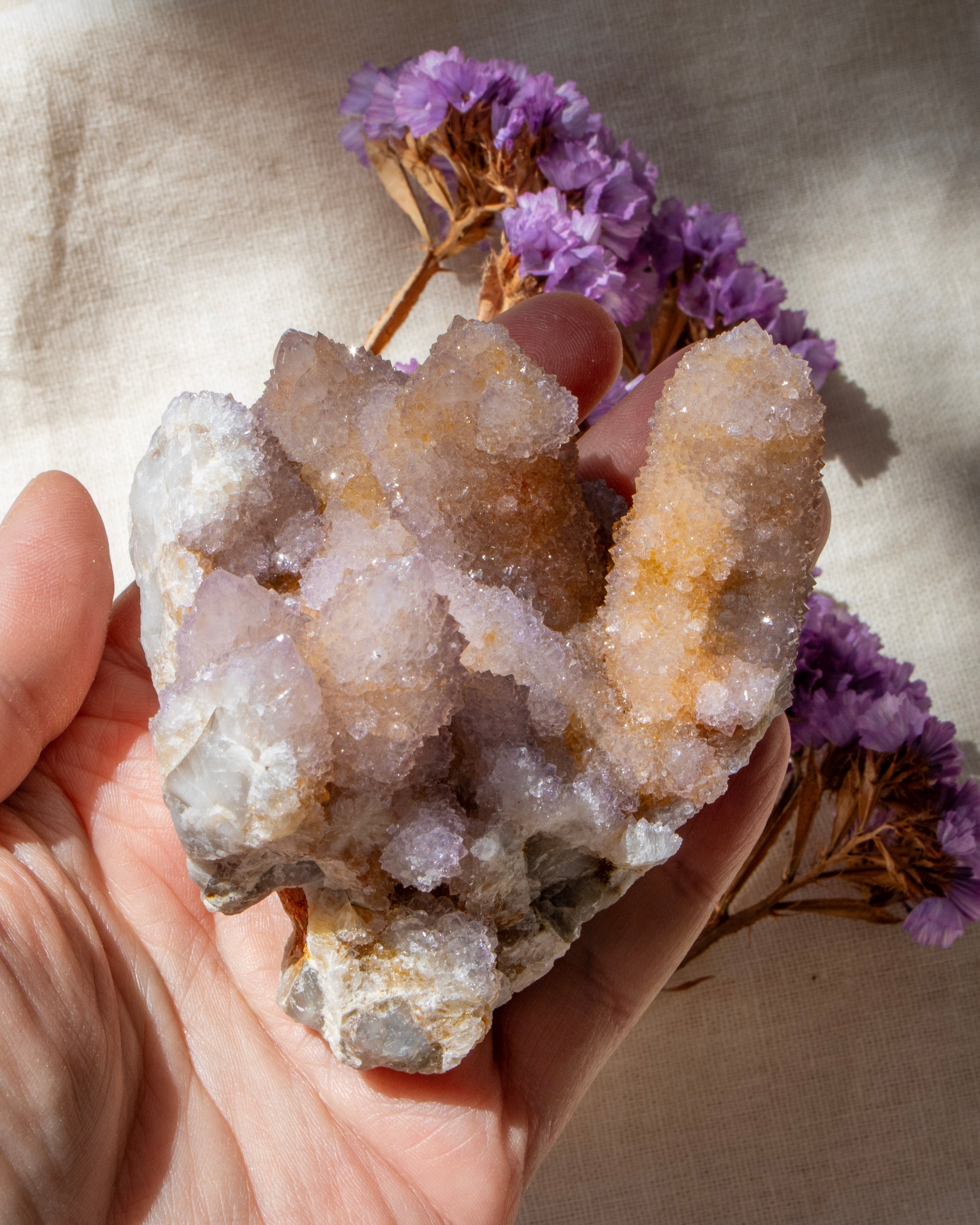 purple crystal cluster being held in a hand with a blurred background