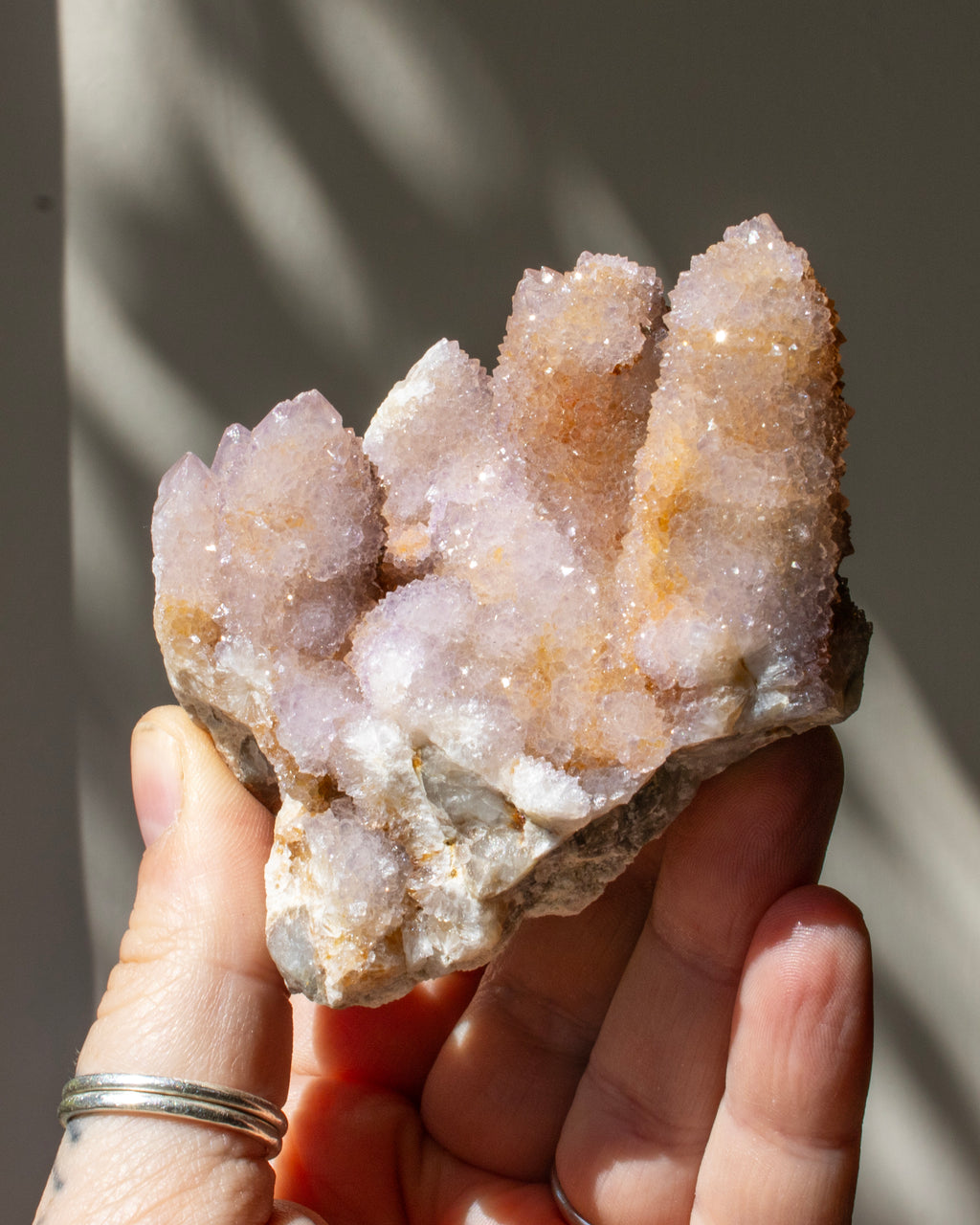 purple crystal cluster being held in a hand with a blurred background