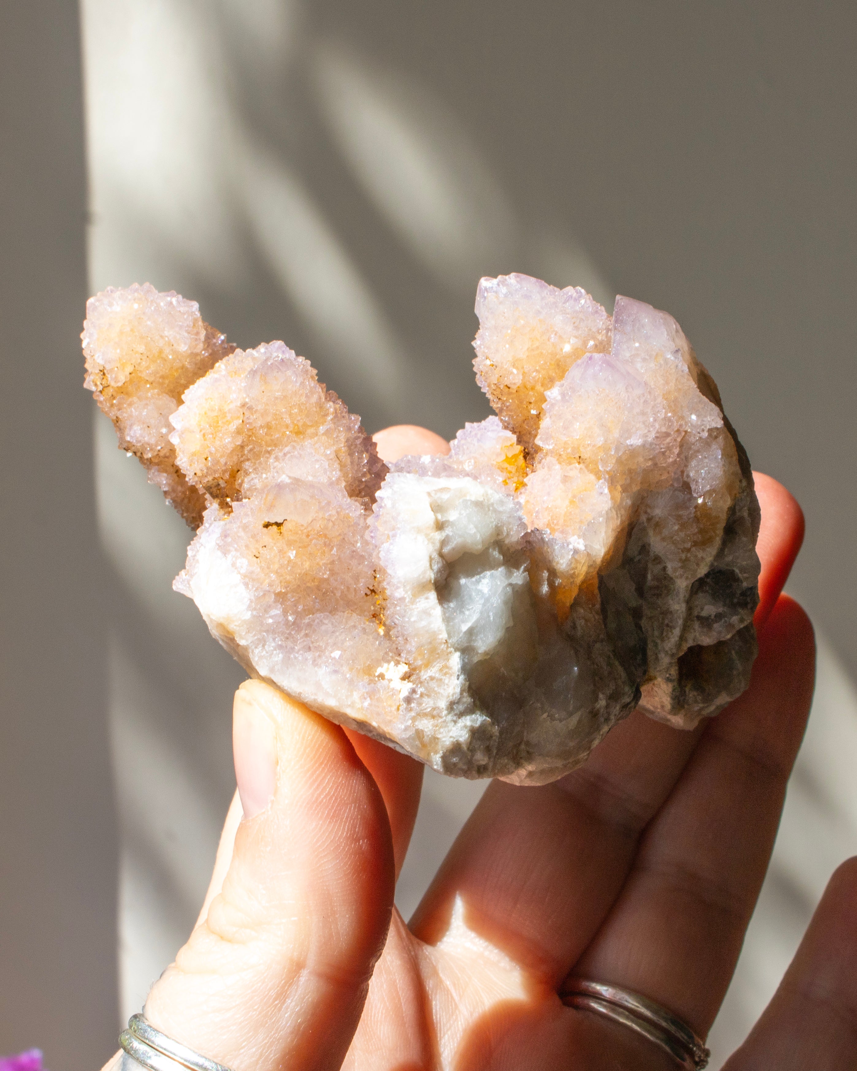 purple crystal cluster being held in a hand with a blurred background