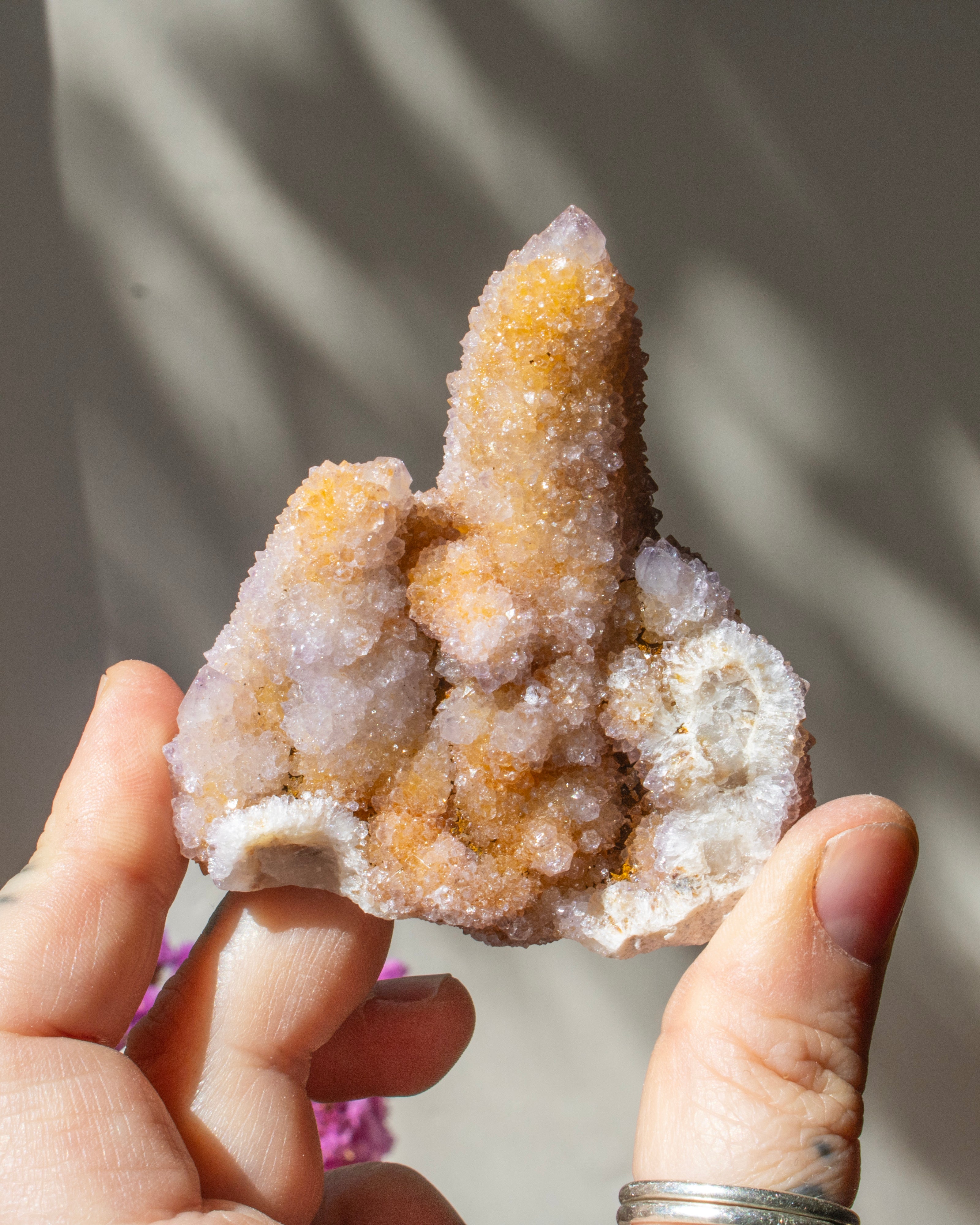 purple crystal cluster being held in a hand with a blurred background