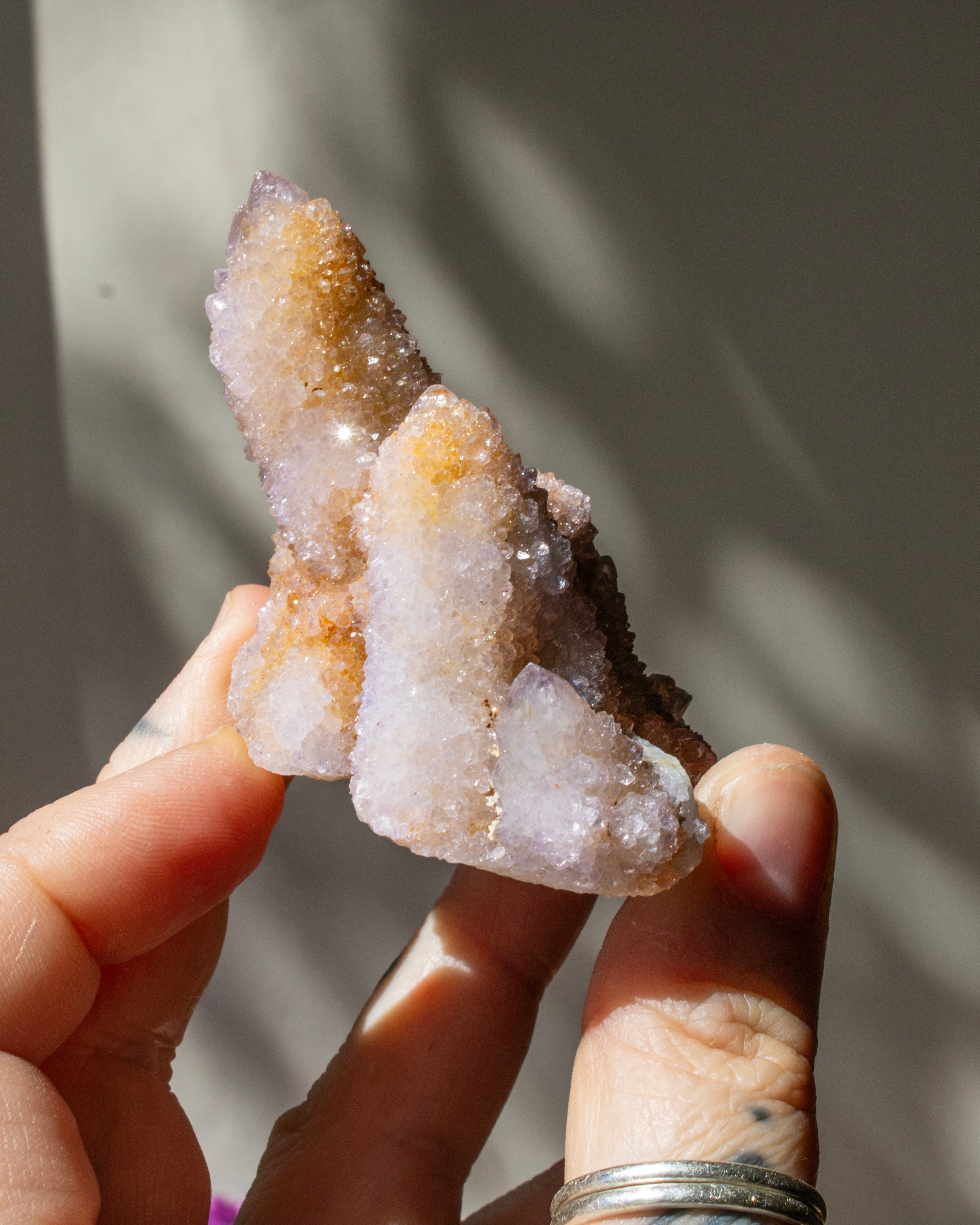 Hand holding a crystal formation against a neutral background