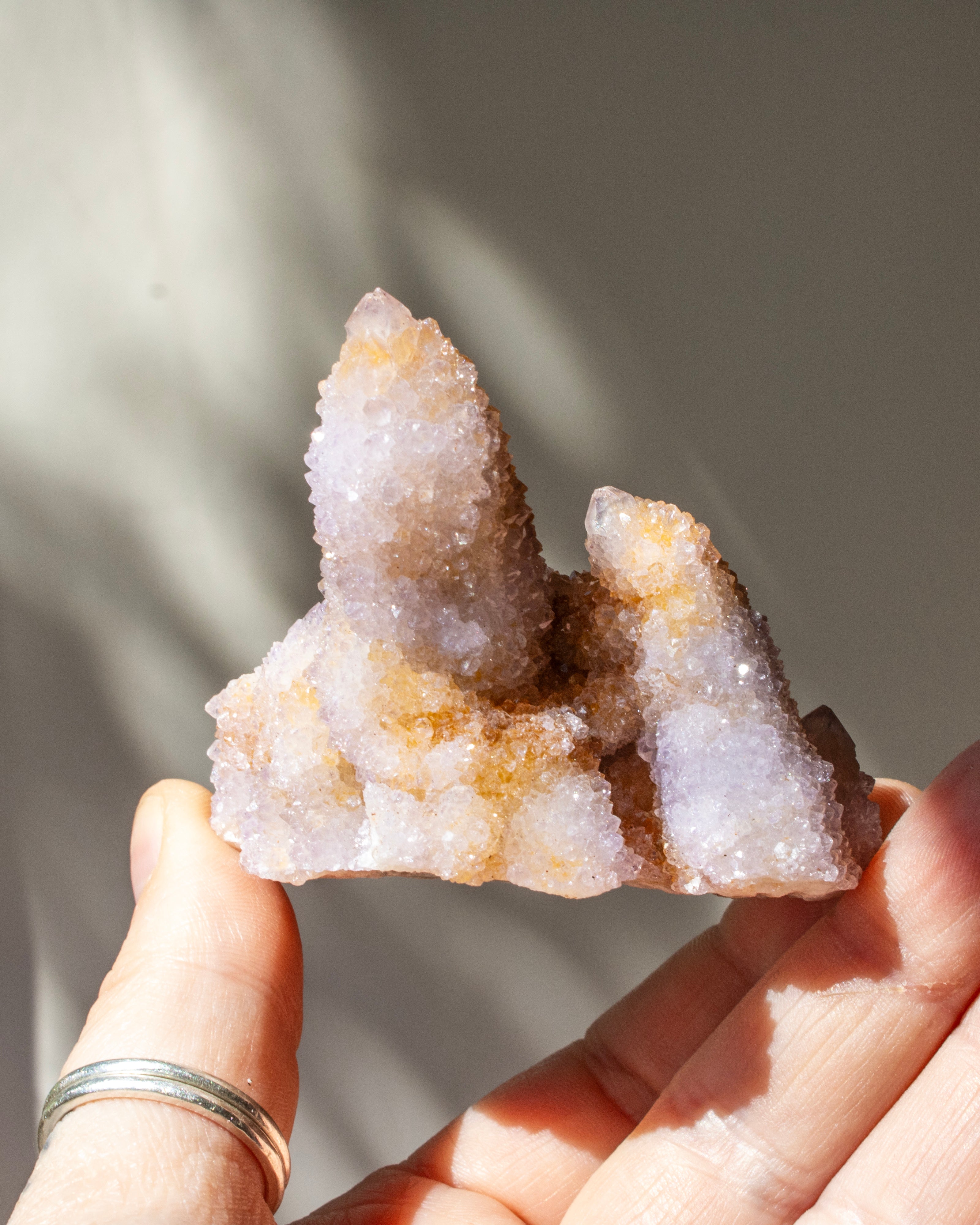 Hand holding a crystal formation against a neutral background