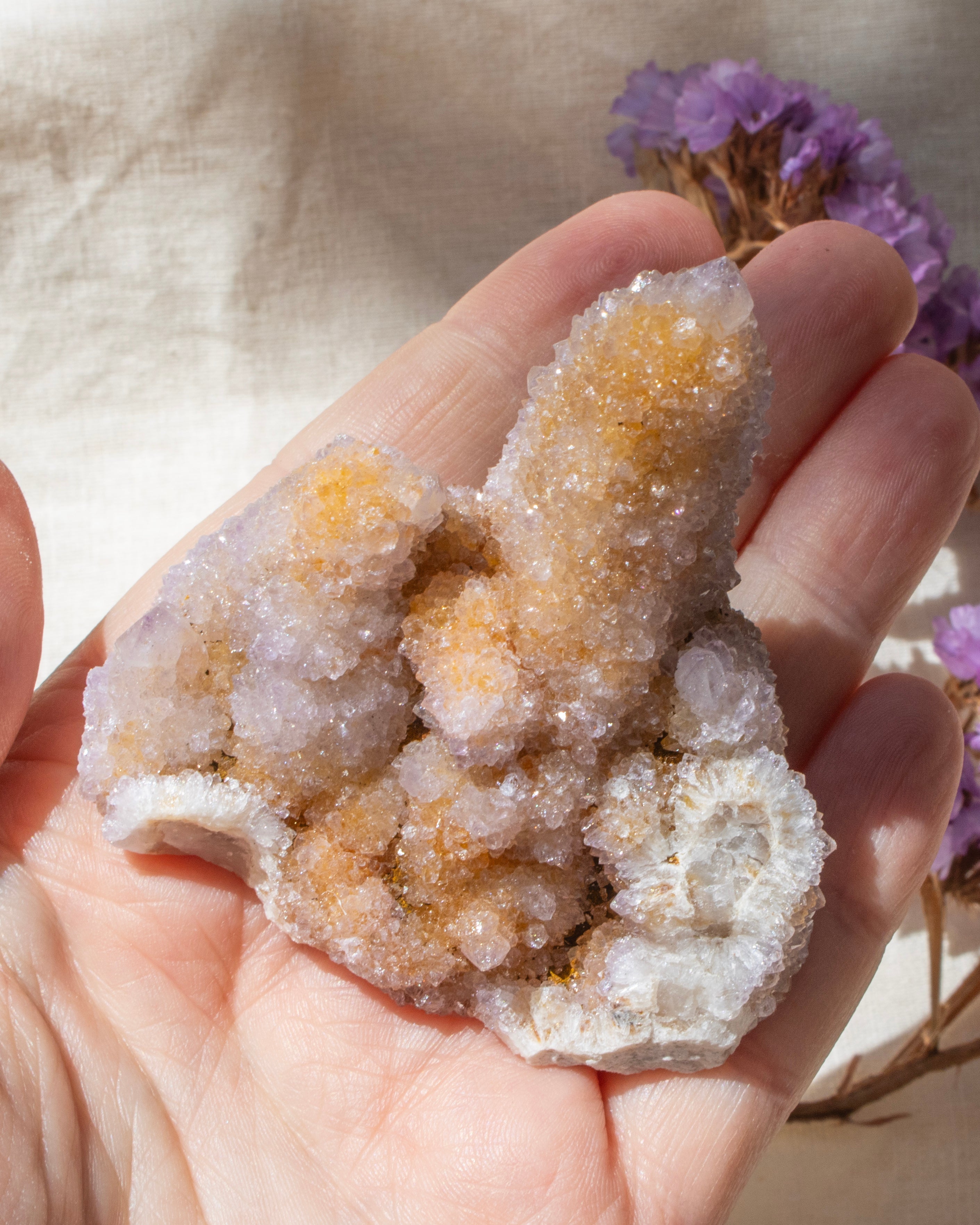 Hand holding a crystal formation against a neutral background