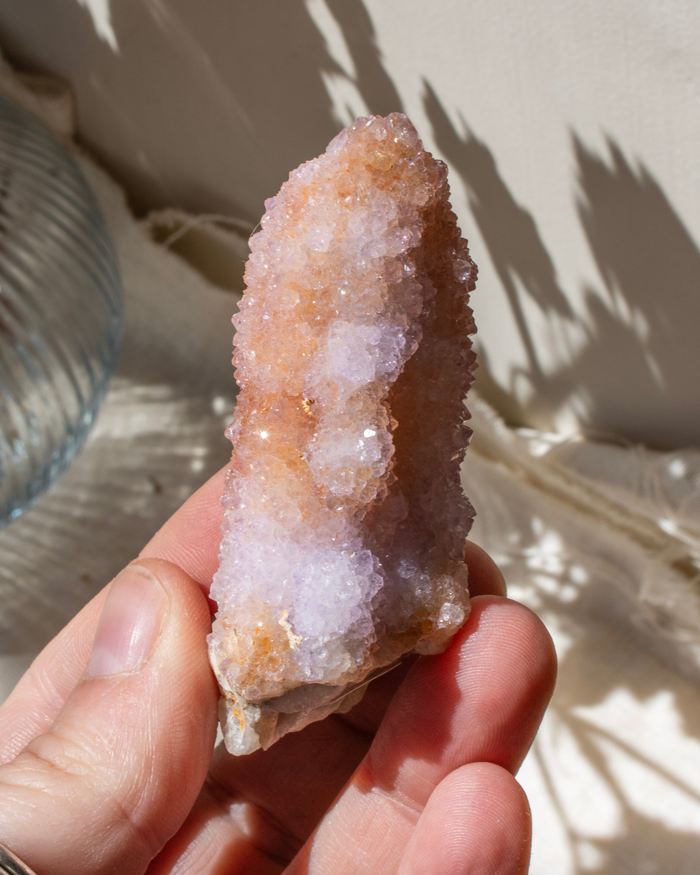 Hand holding a crystal with a beige and white coloration against a neutral background