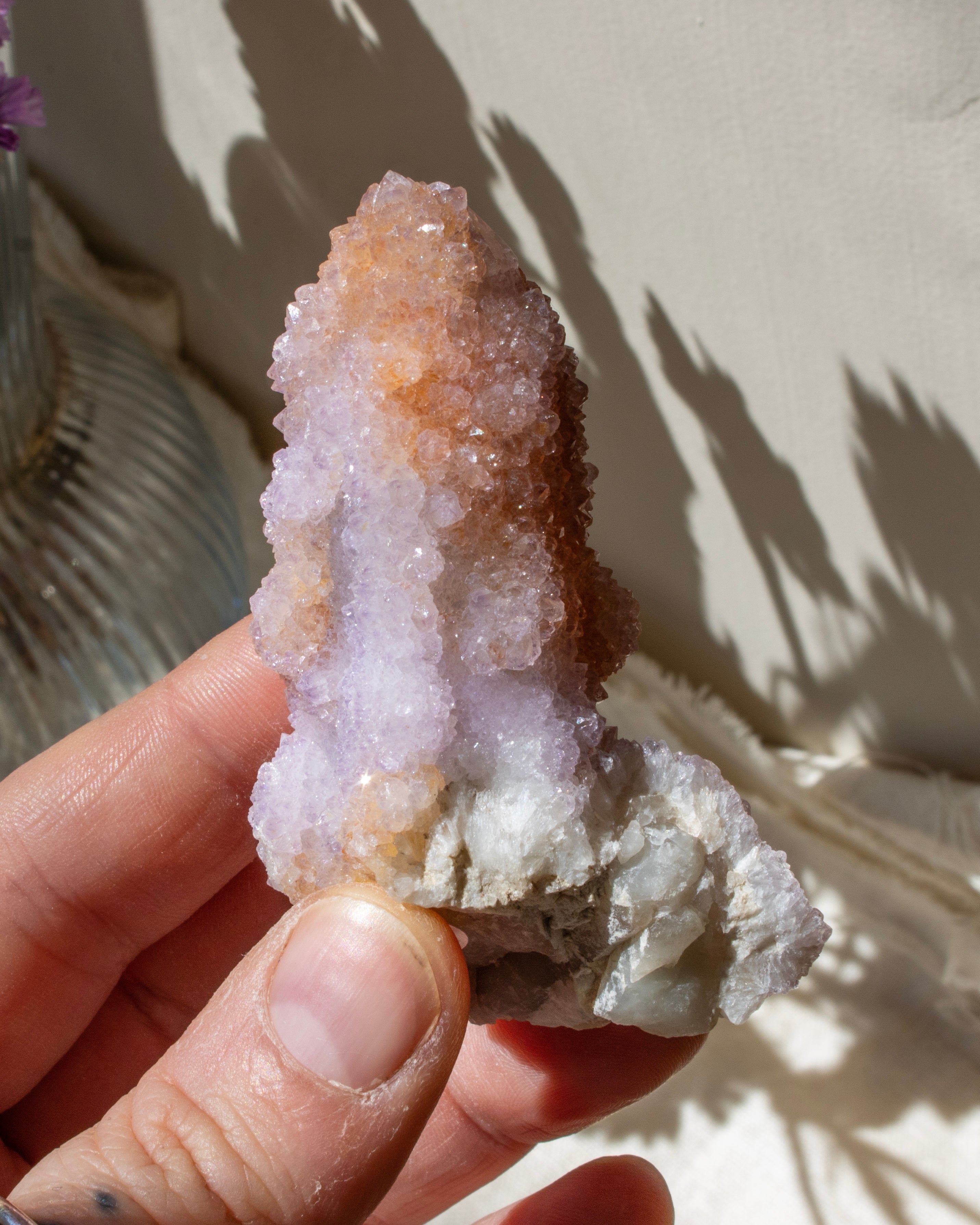 Hand holding a crystal formation against a neutral background
