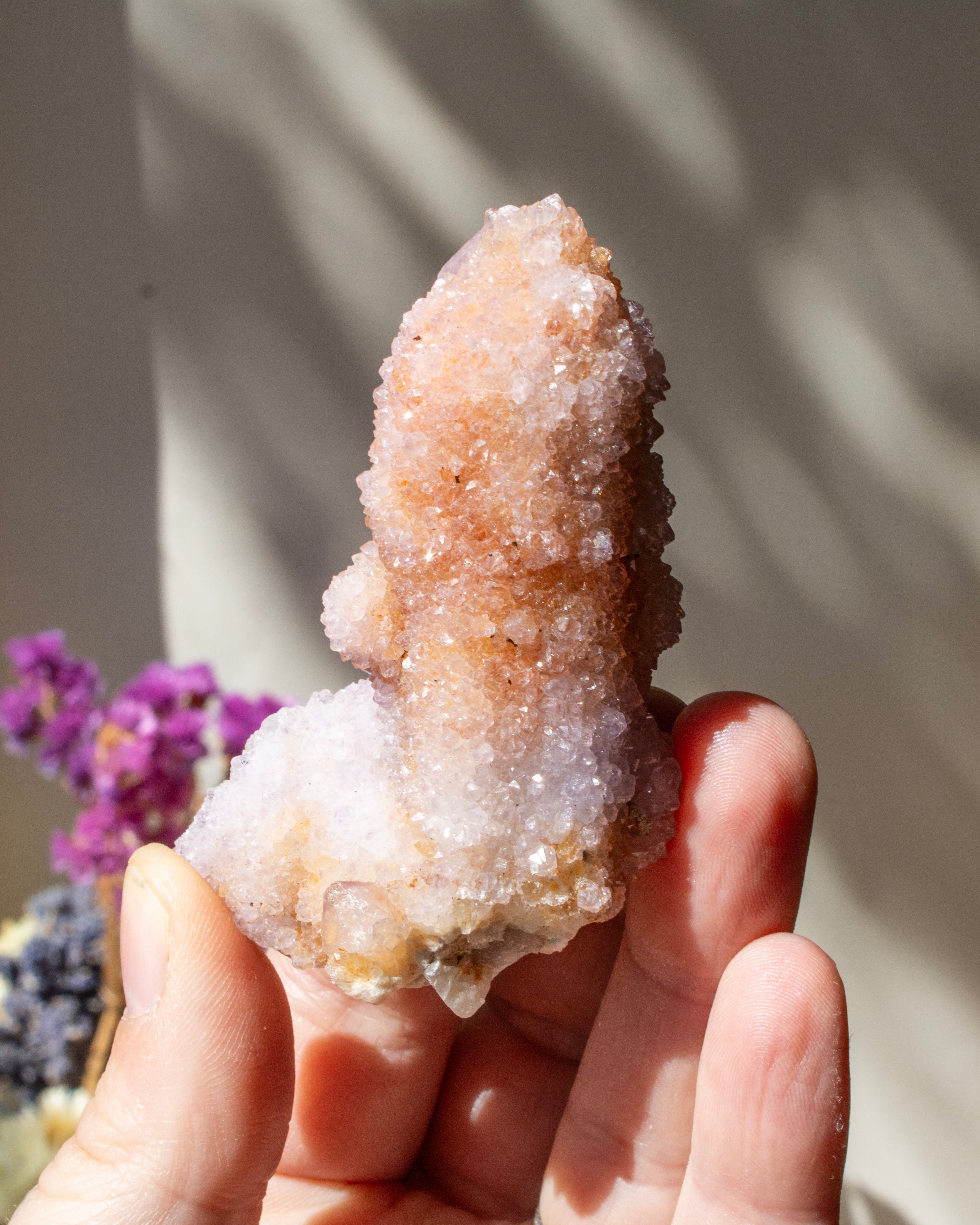 Hand holding a crystal formation with a blurred natural background