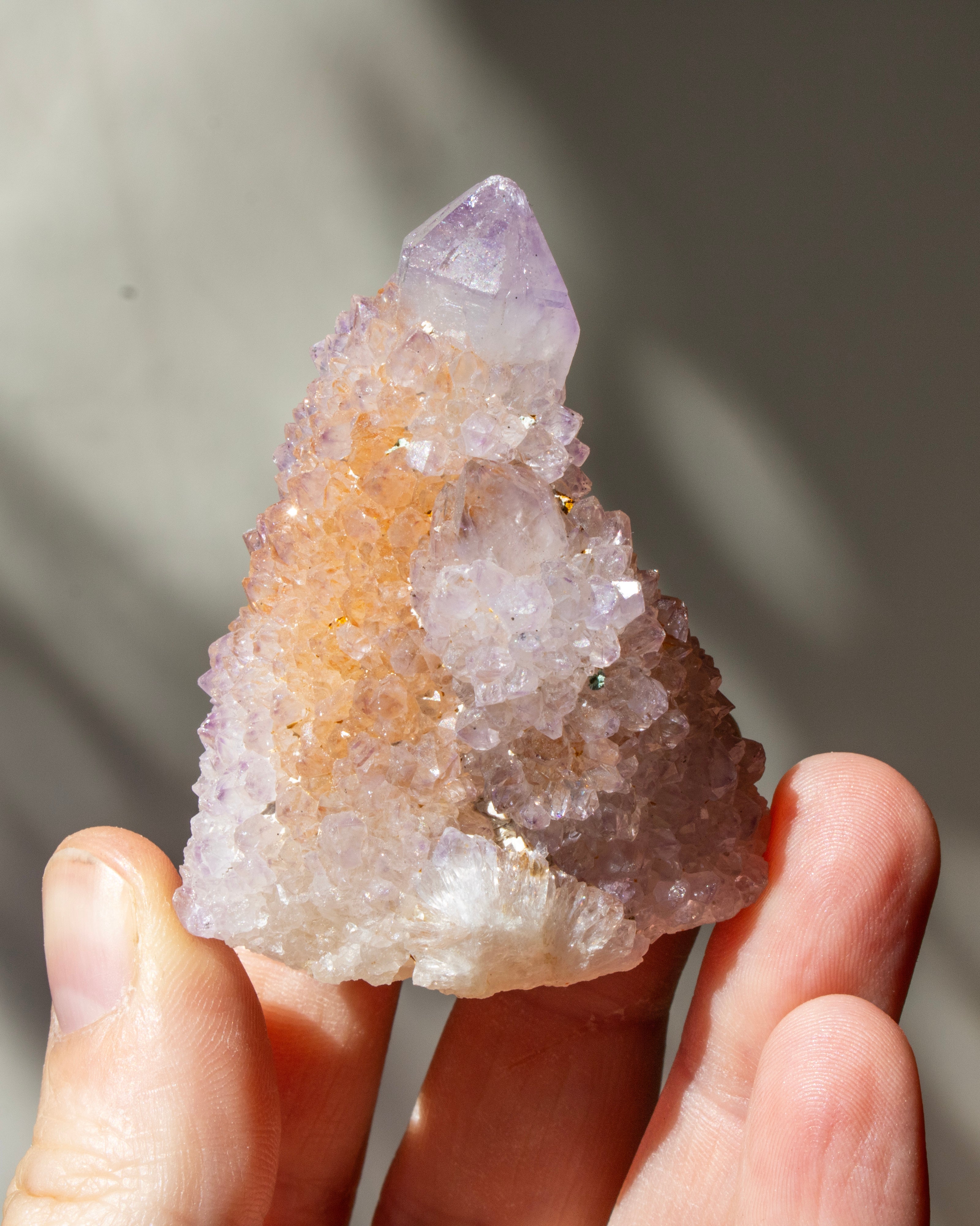 Hand holding a crystal cluster with a blurred natural background