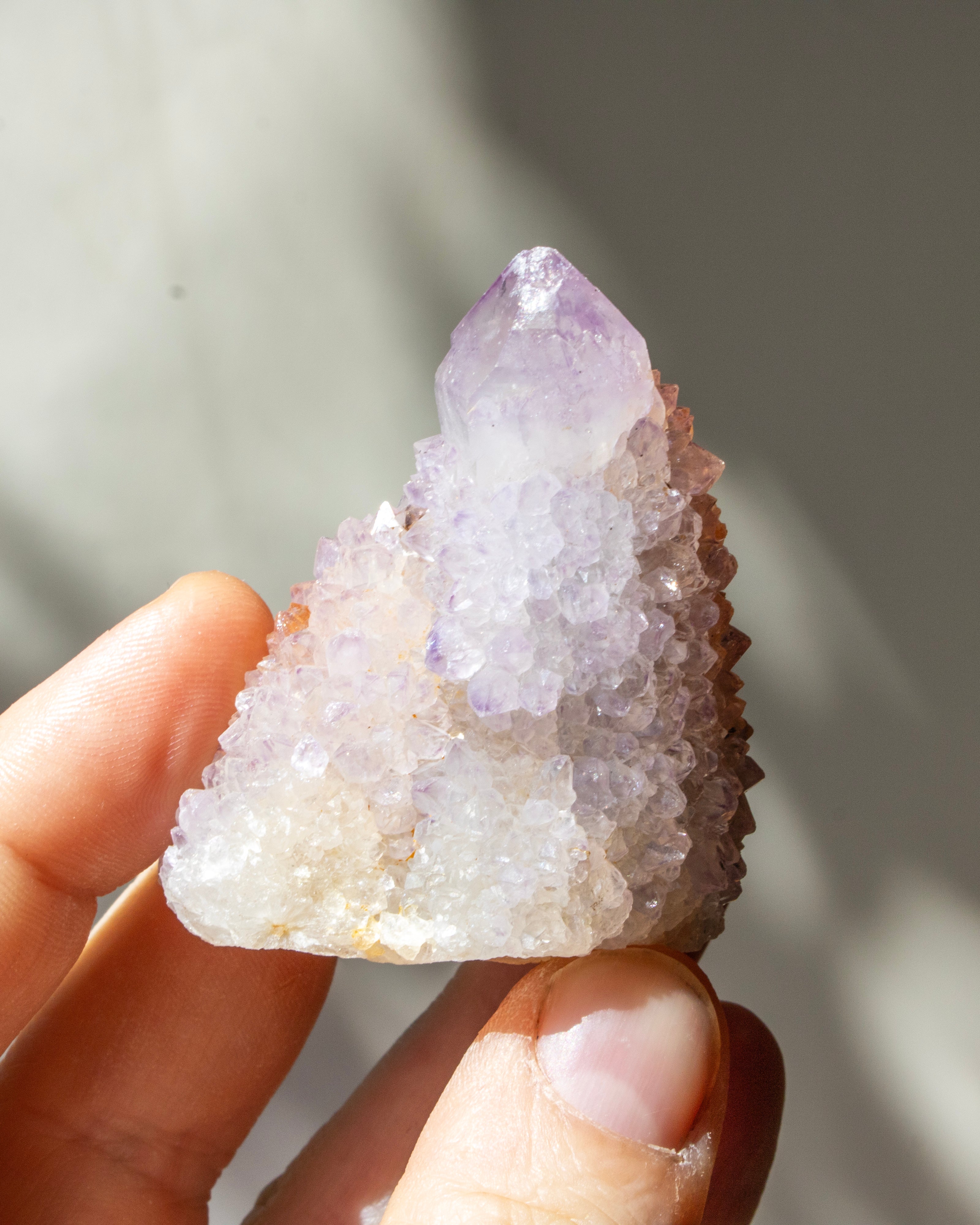 Hand holding a crystal cluster with a blurred natural background