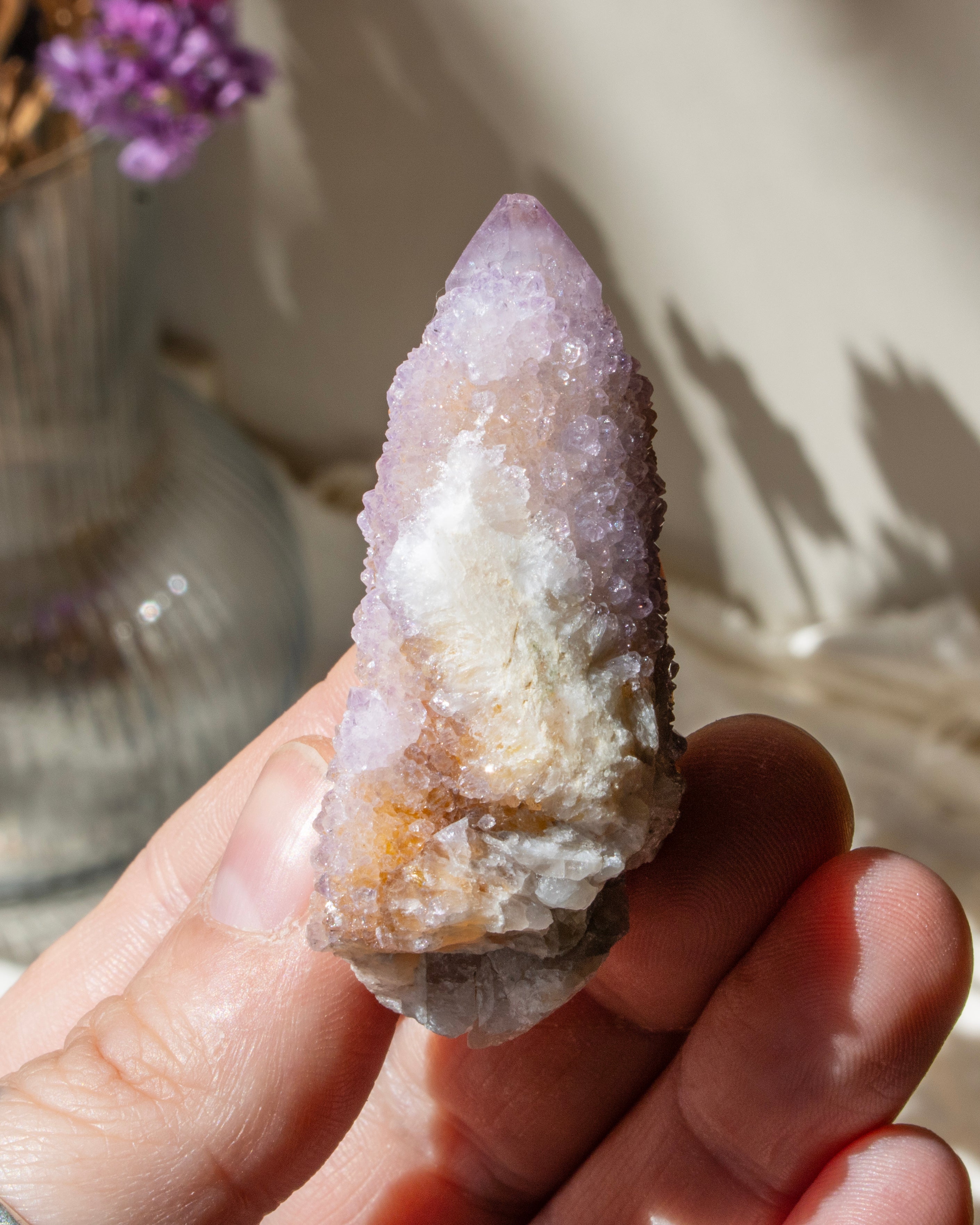 hand holding a purple crystal cluster with a blurred background