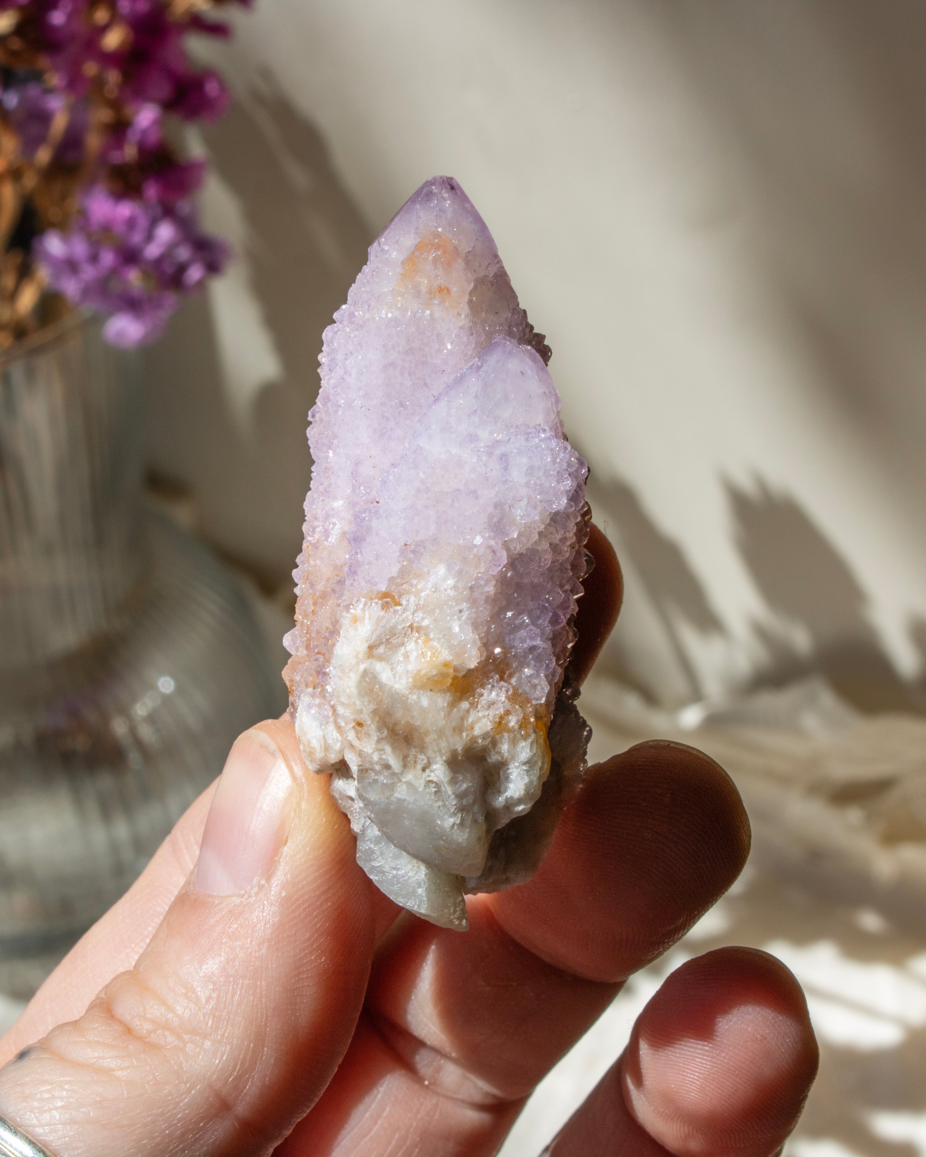 hand holding a purple crystal cluster with a blurred background