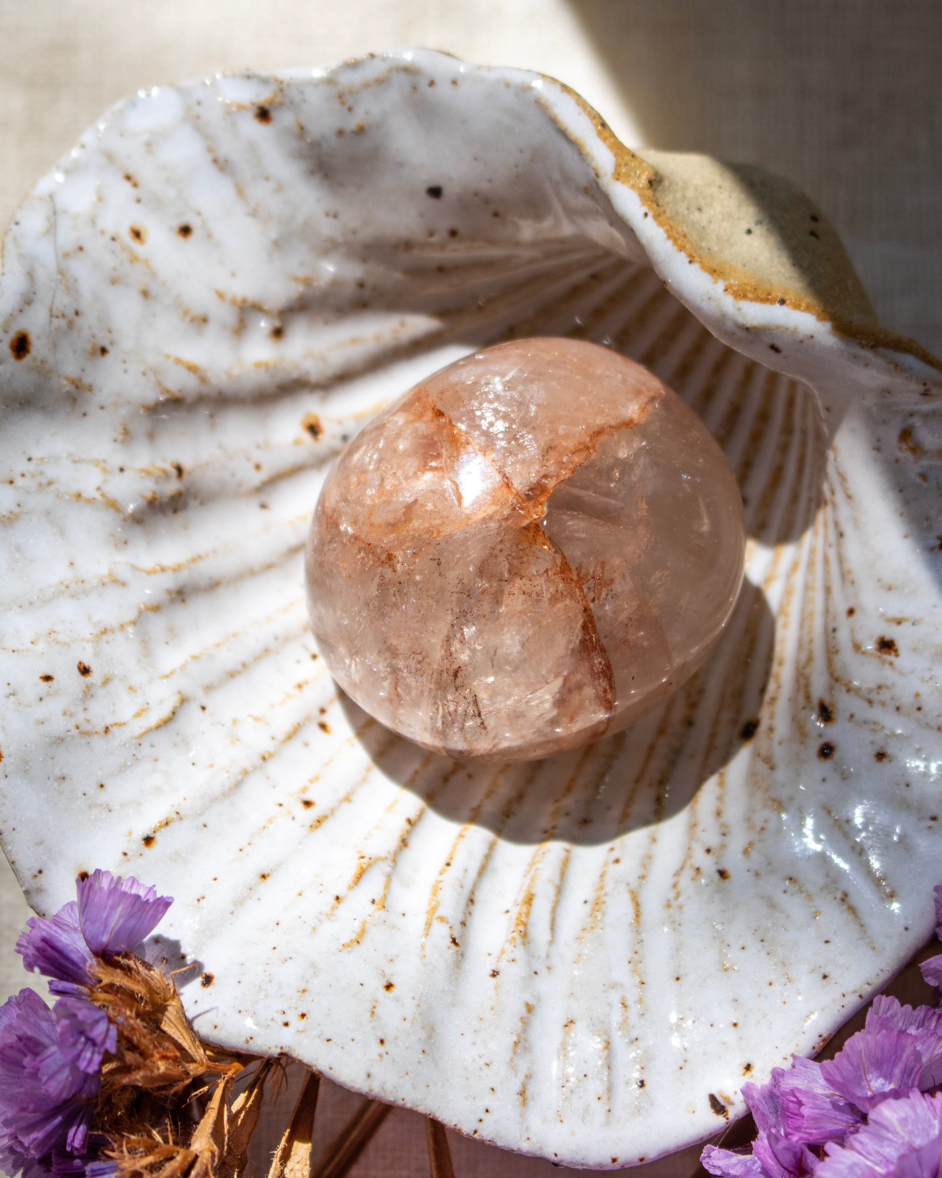 Crystal ball on a seashell with purple flowers