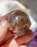 Clear crystal held in a hand with a blurred background