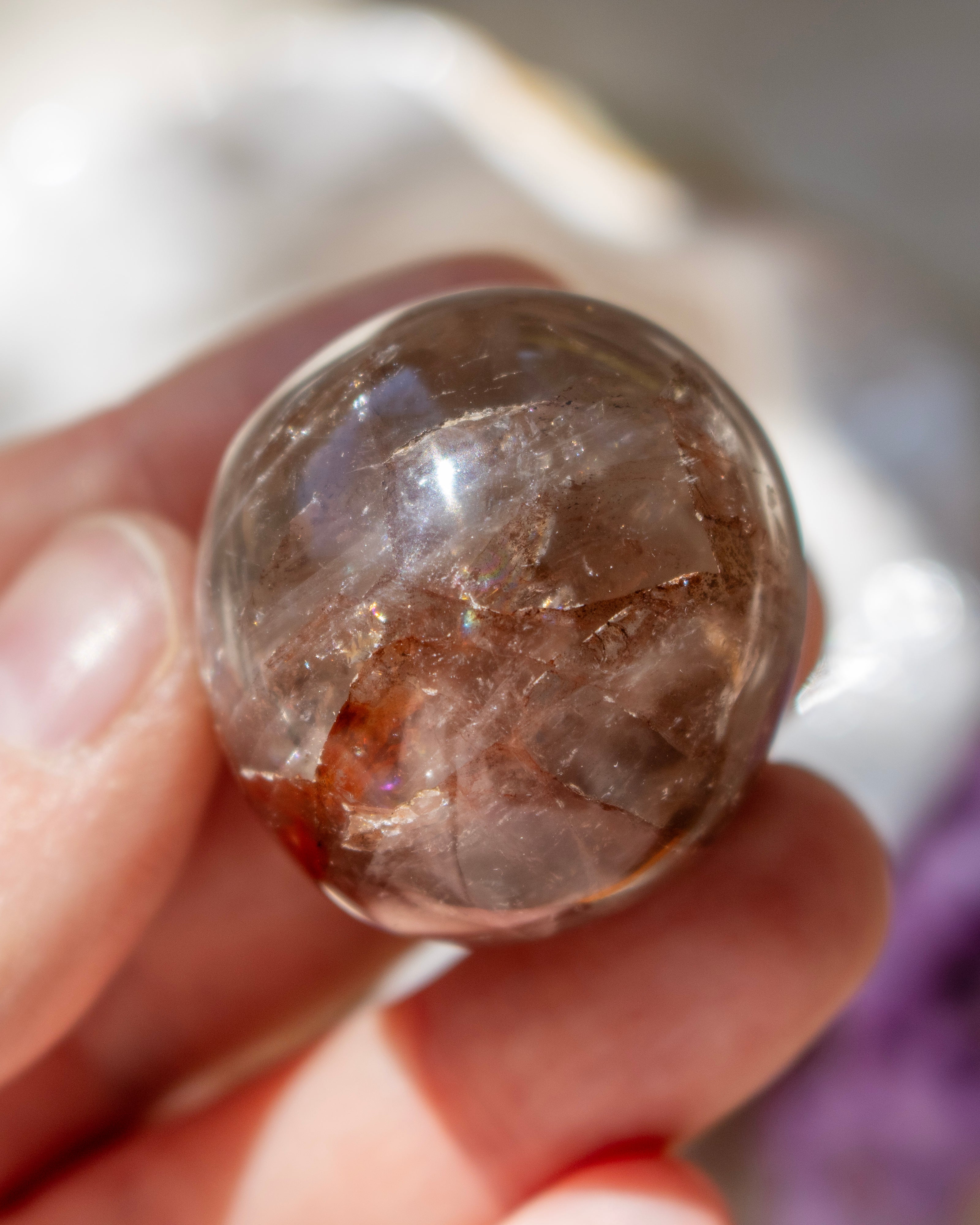 Clear crystal held in a hand with a blurred background