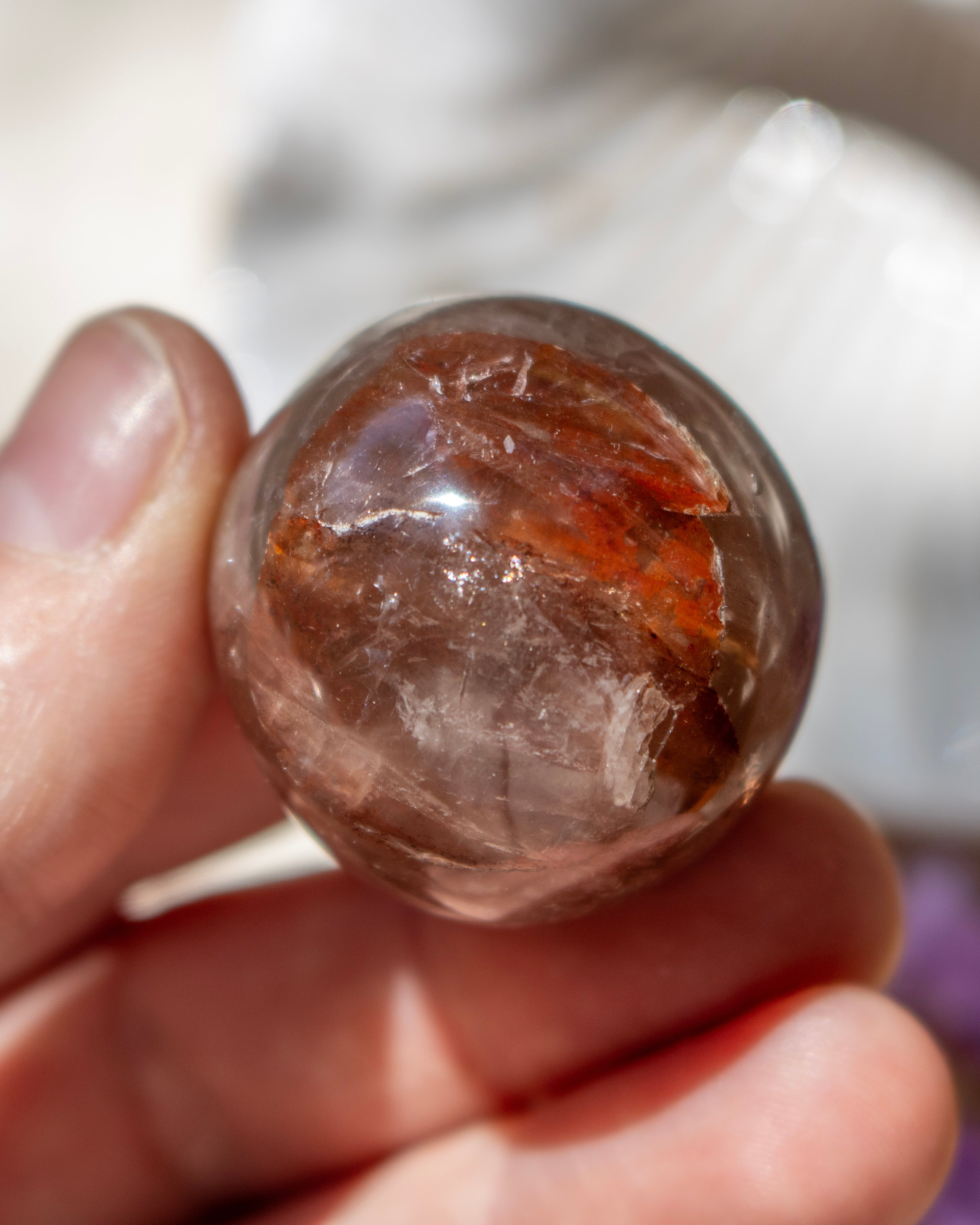 Clear crystal ball held in a hand with a blurred background