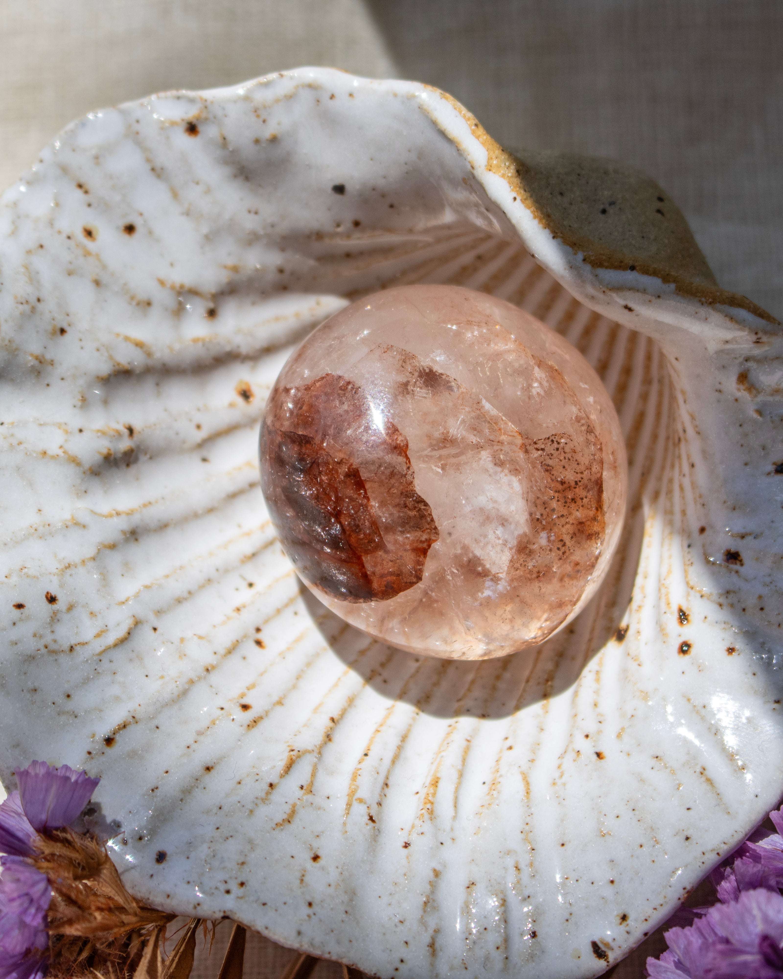 Crystal ball inside a shell with purple flowers at the base