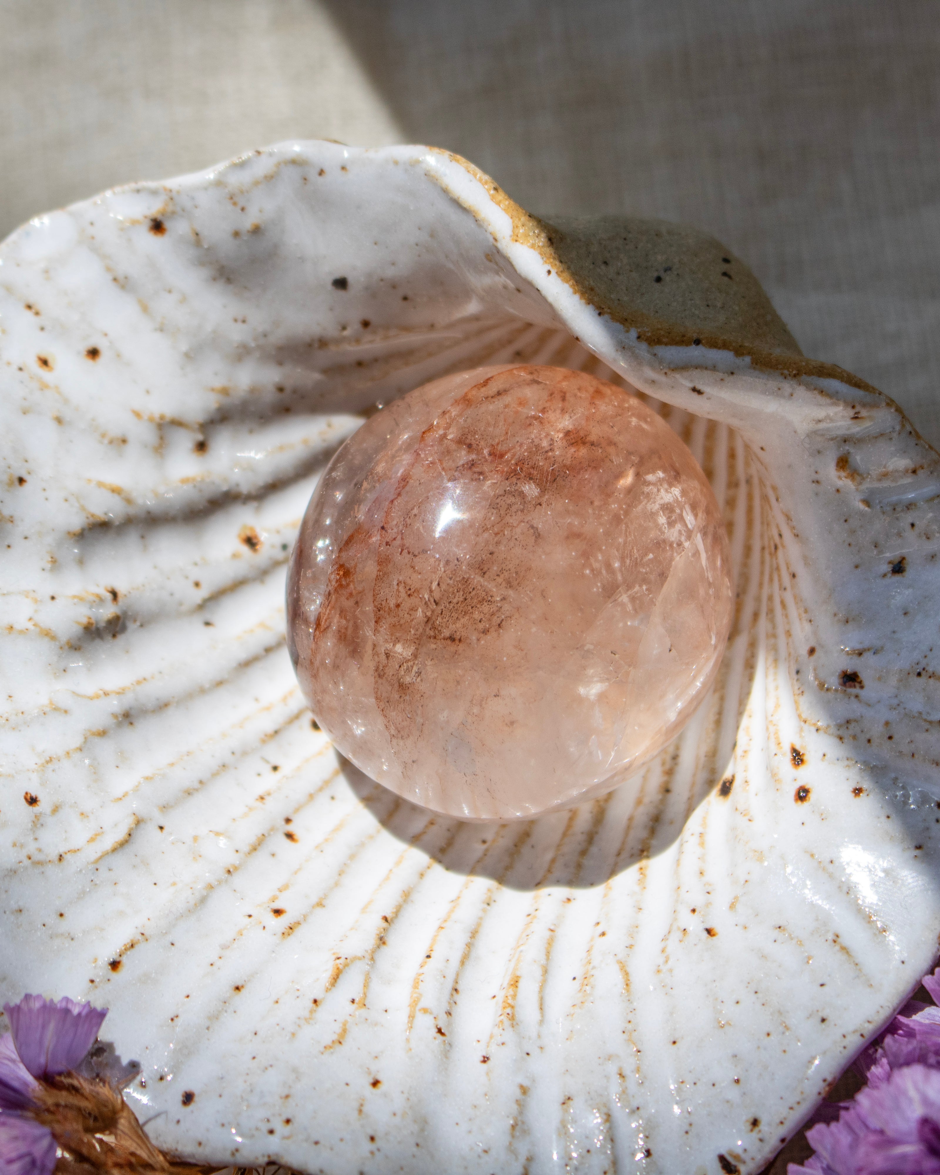 Crystal ball inside a seashell with purple flowers at the base