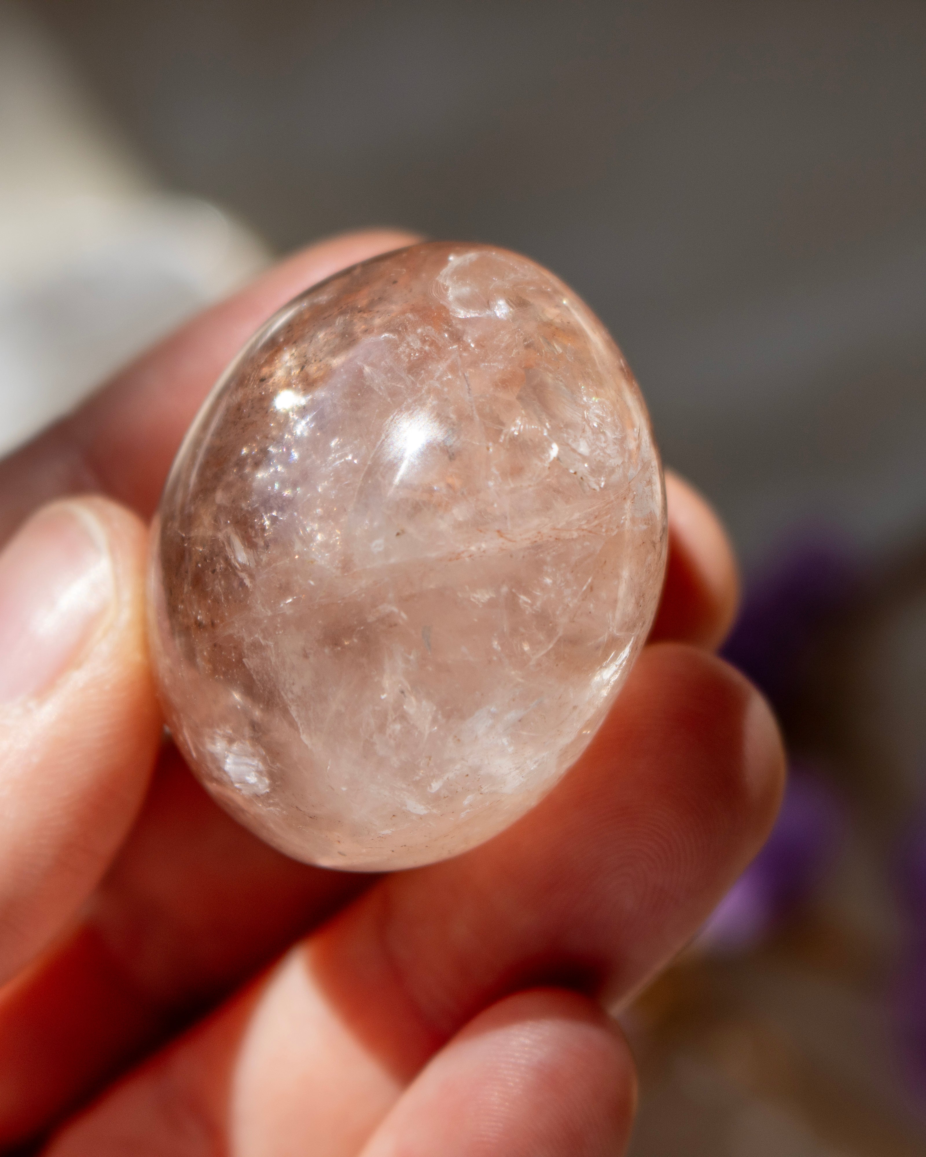 Clear crystal held in a hand with a blurred background