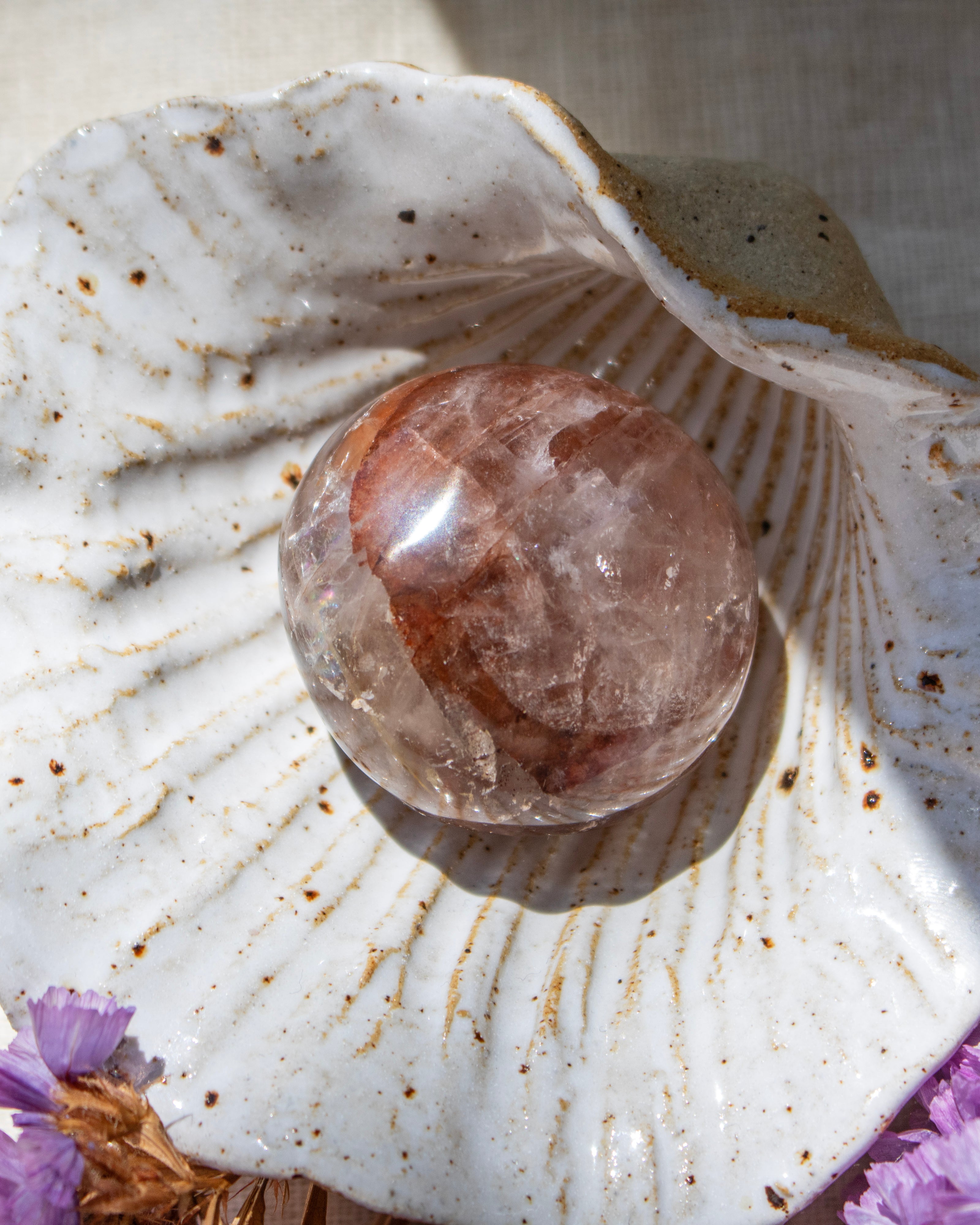 Crystal ball on a seashell with purple flowers