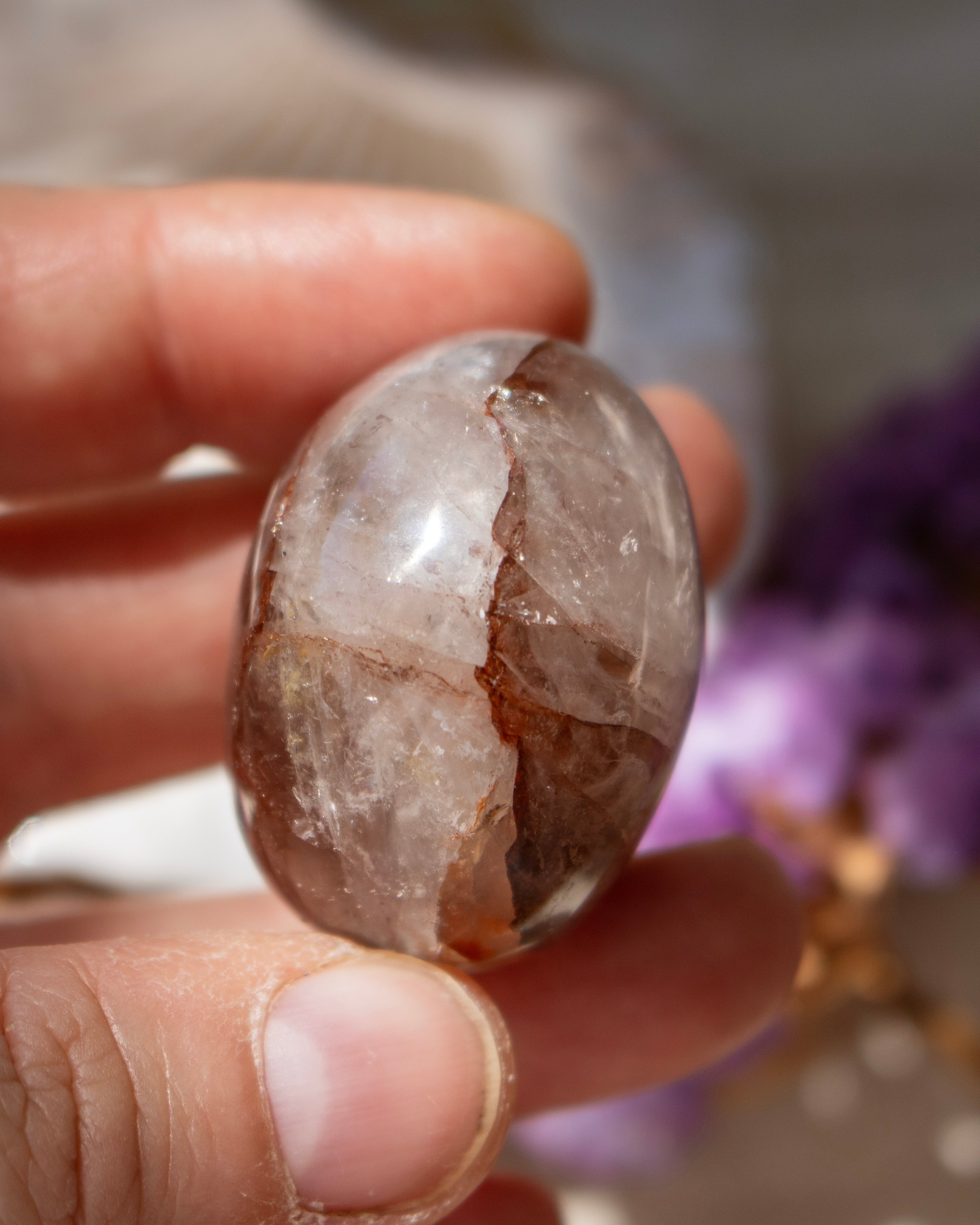 Hand holding a polished stone with a blurred natural background