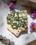 Decorative stone with a unique pattern on a white surface with purple flowers.