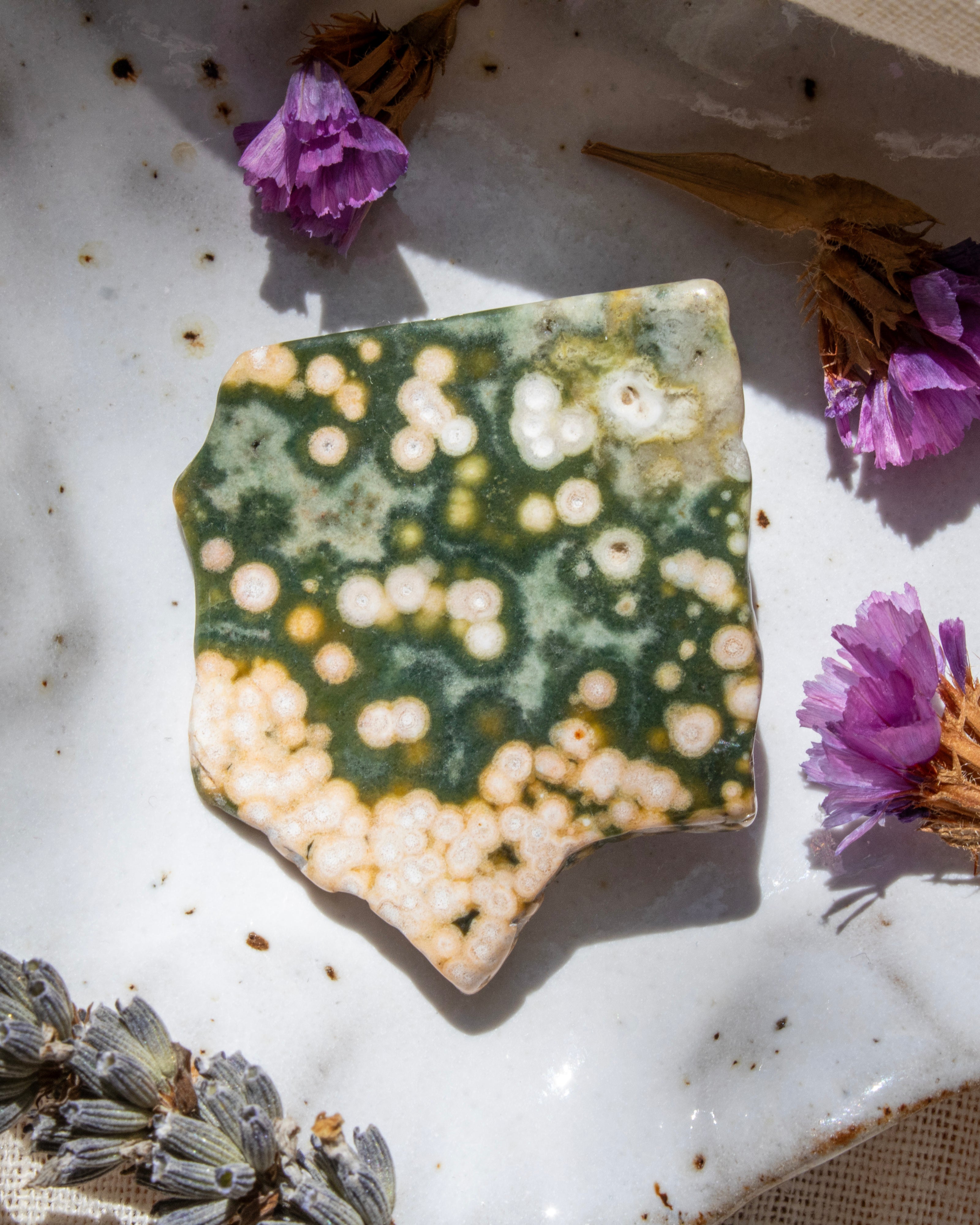 Decorative stone with a unique pattern on a white surface with purple flowers.