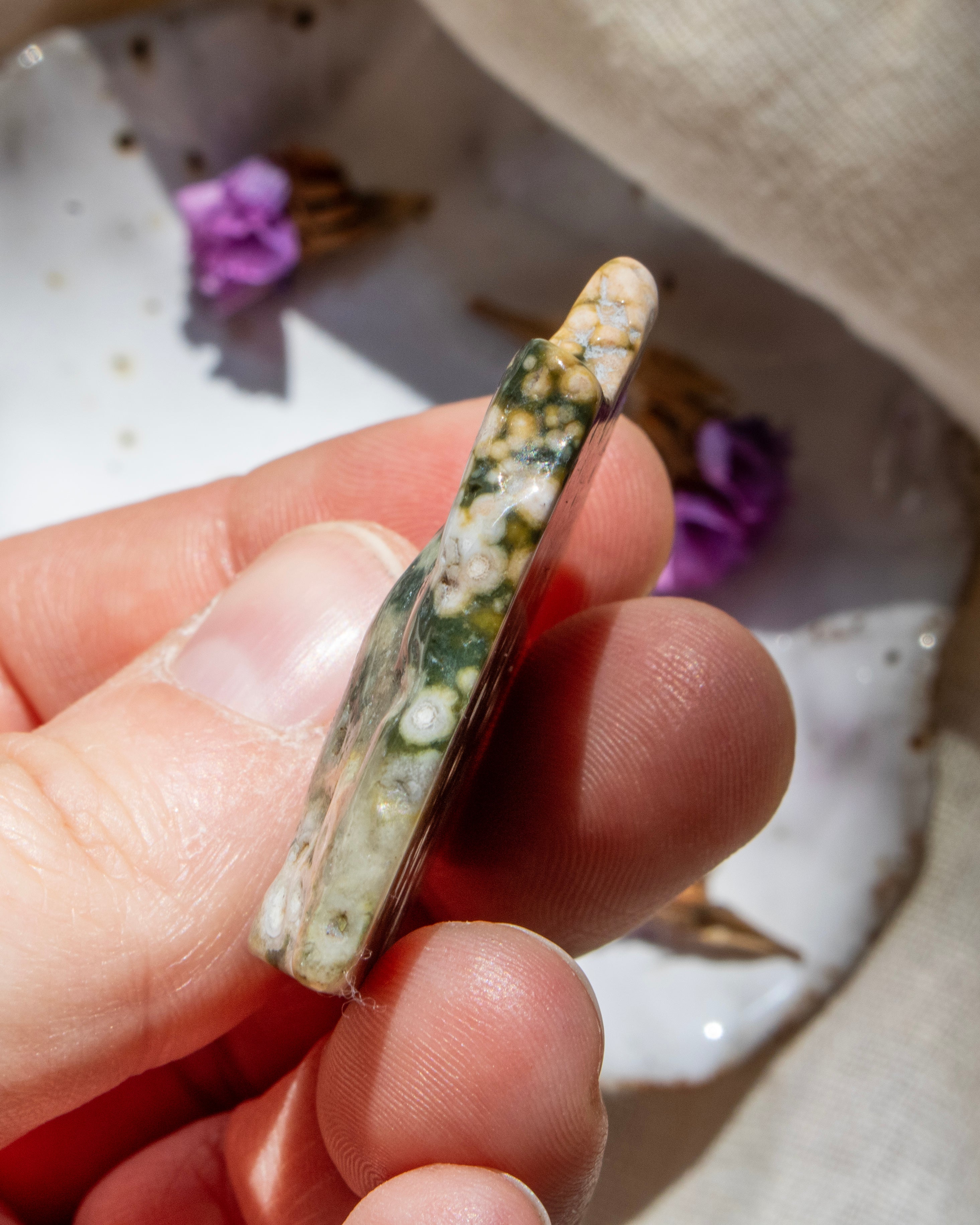 Hand holding a multicolored stone with a blurred background