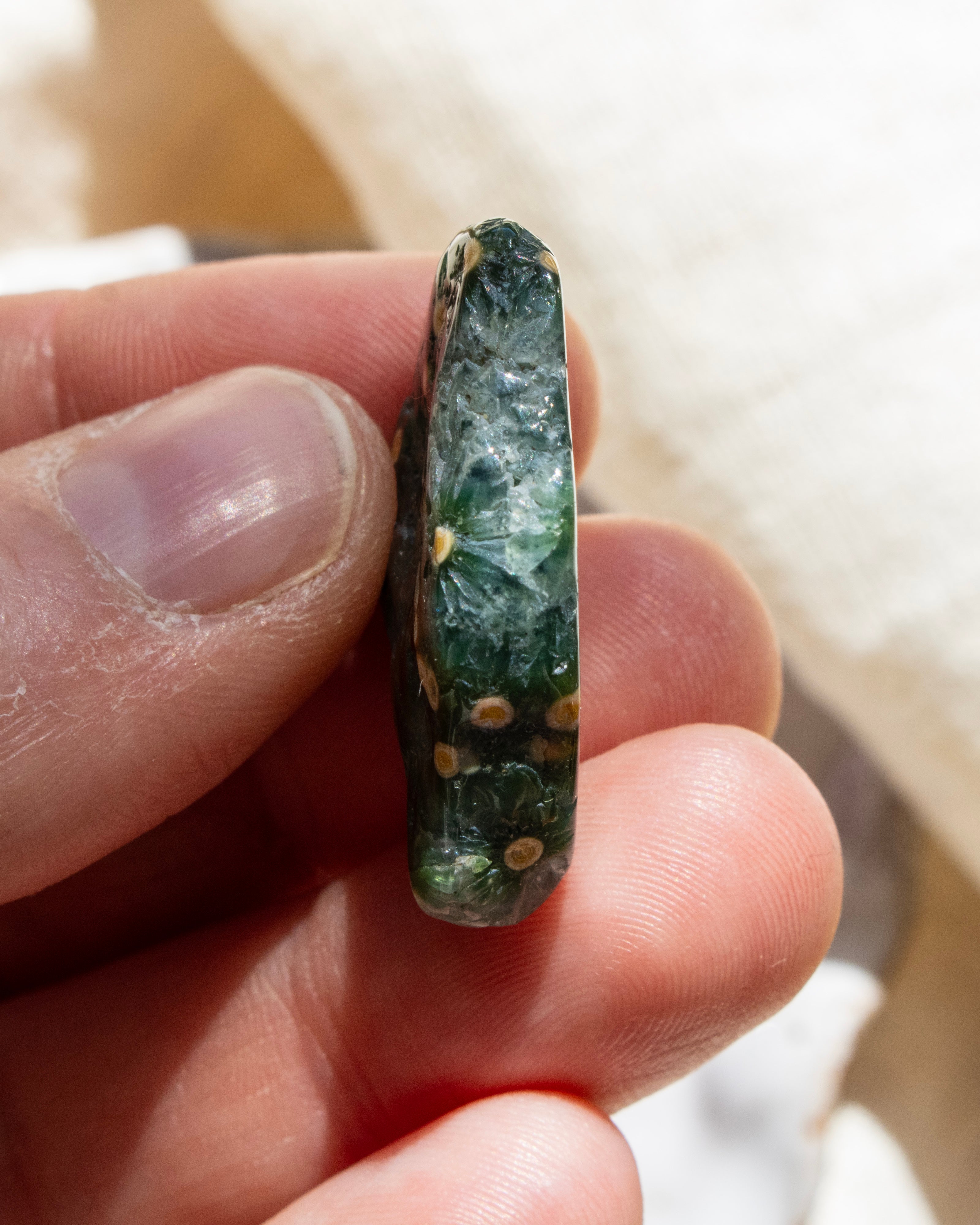 Hand holding a green stone with a blurred background