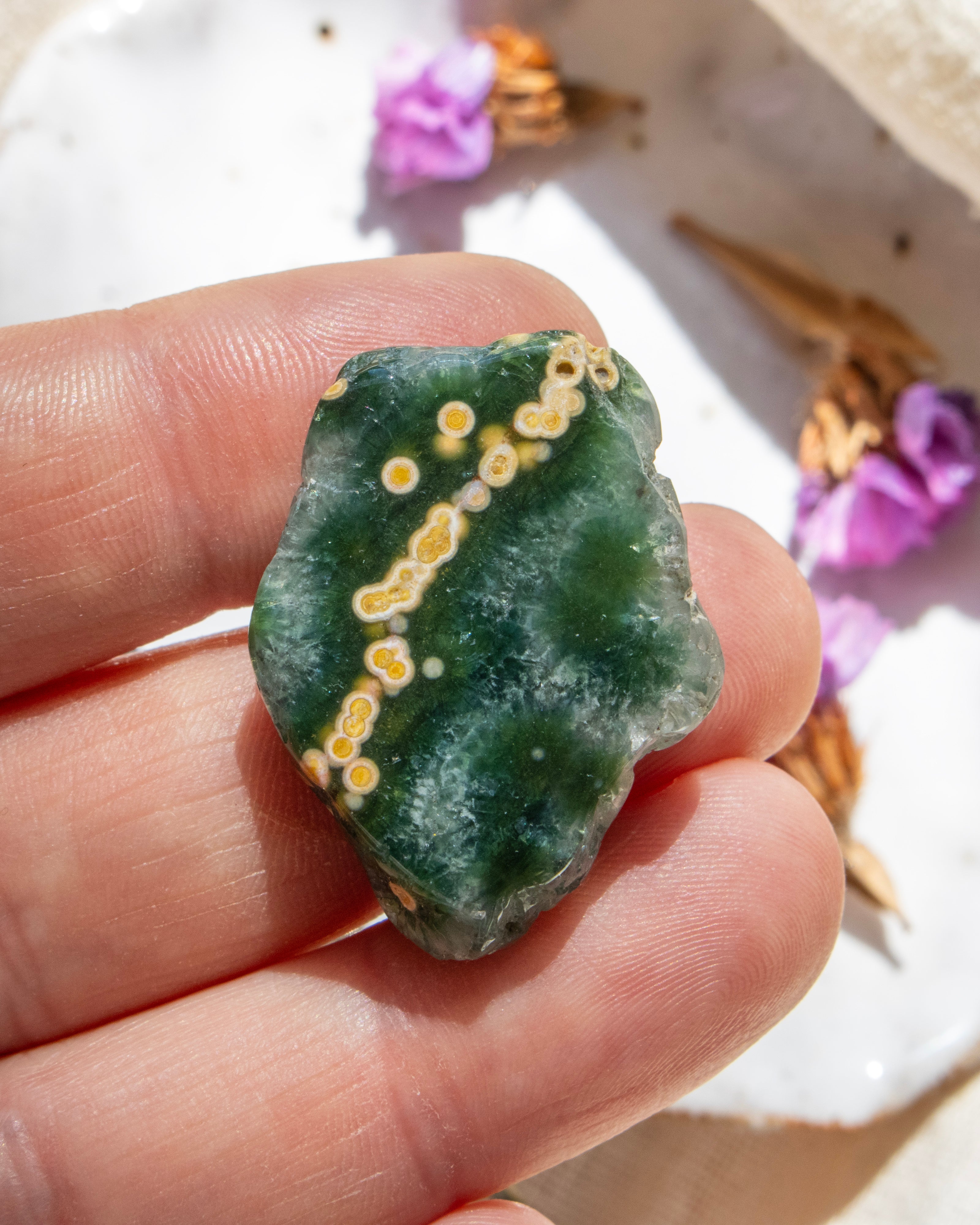 Green stone with yellow markings held in a hand, with blurred background