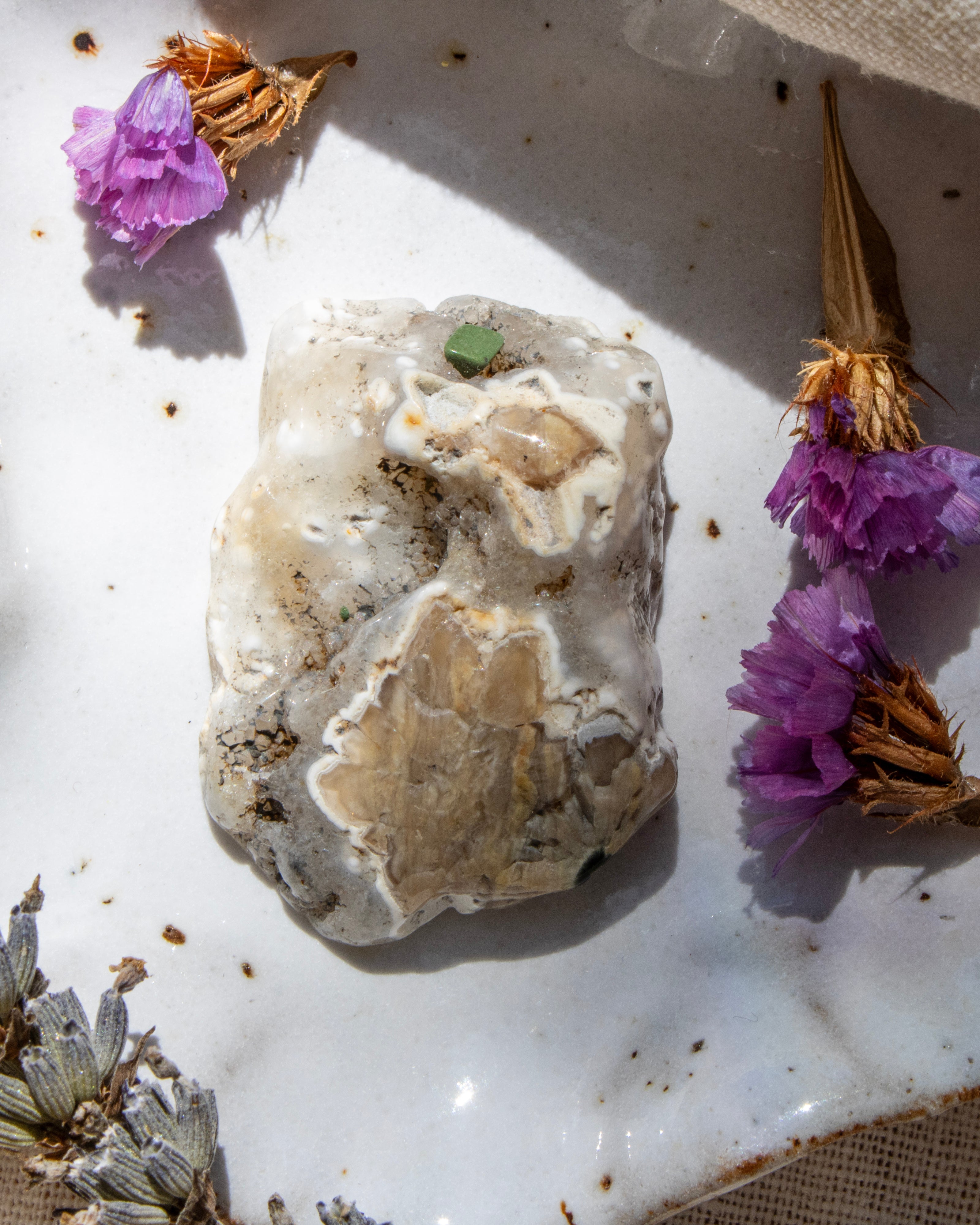 Mineral sample with purple flowers on a textured surface