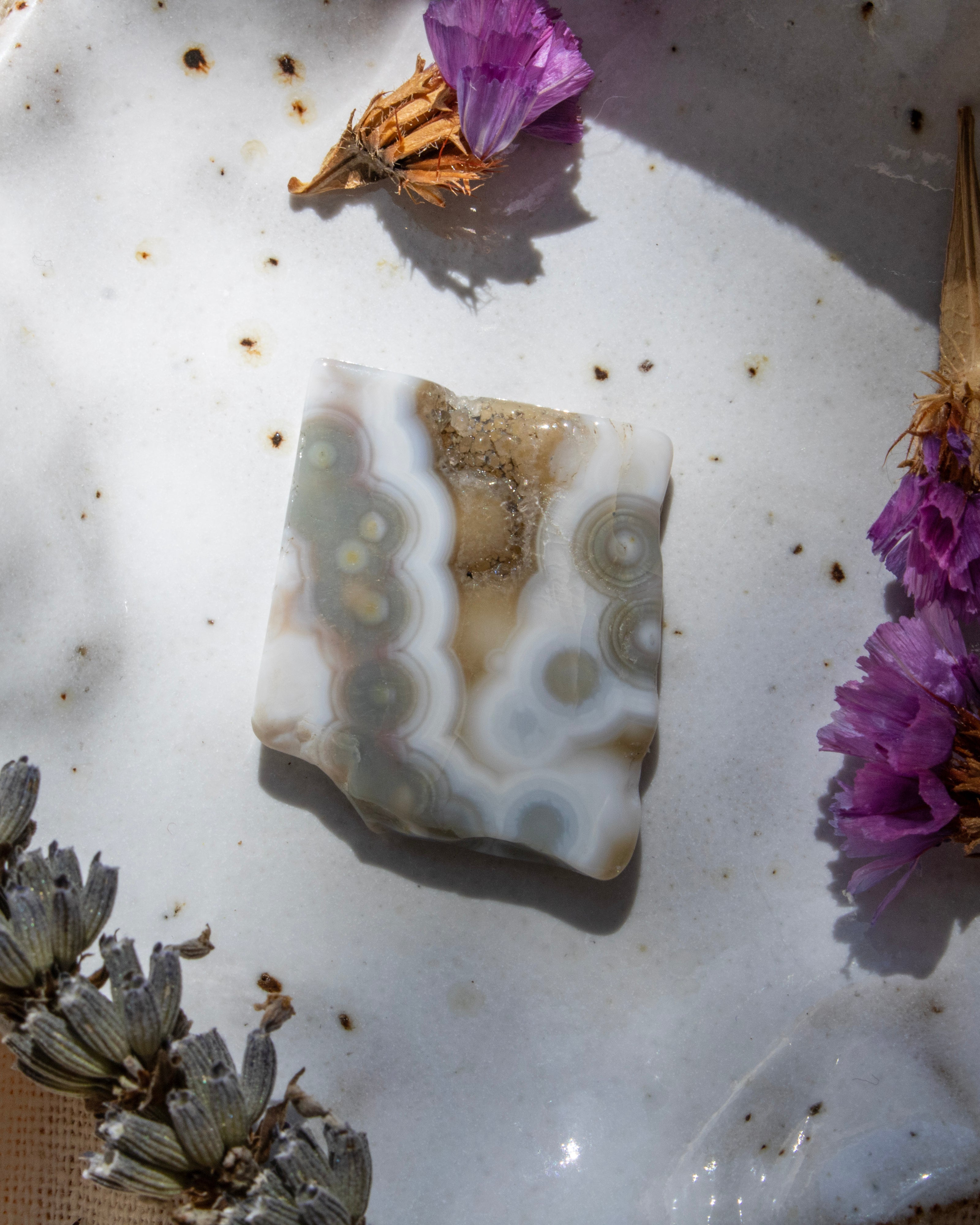 Geode crystal on a white surface with purple flowers