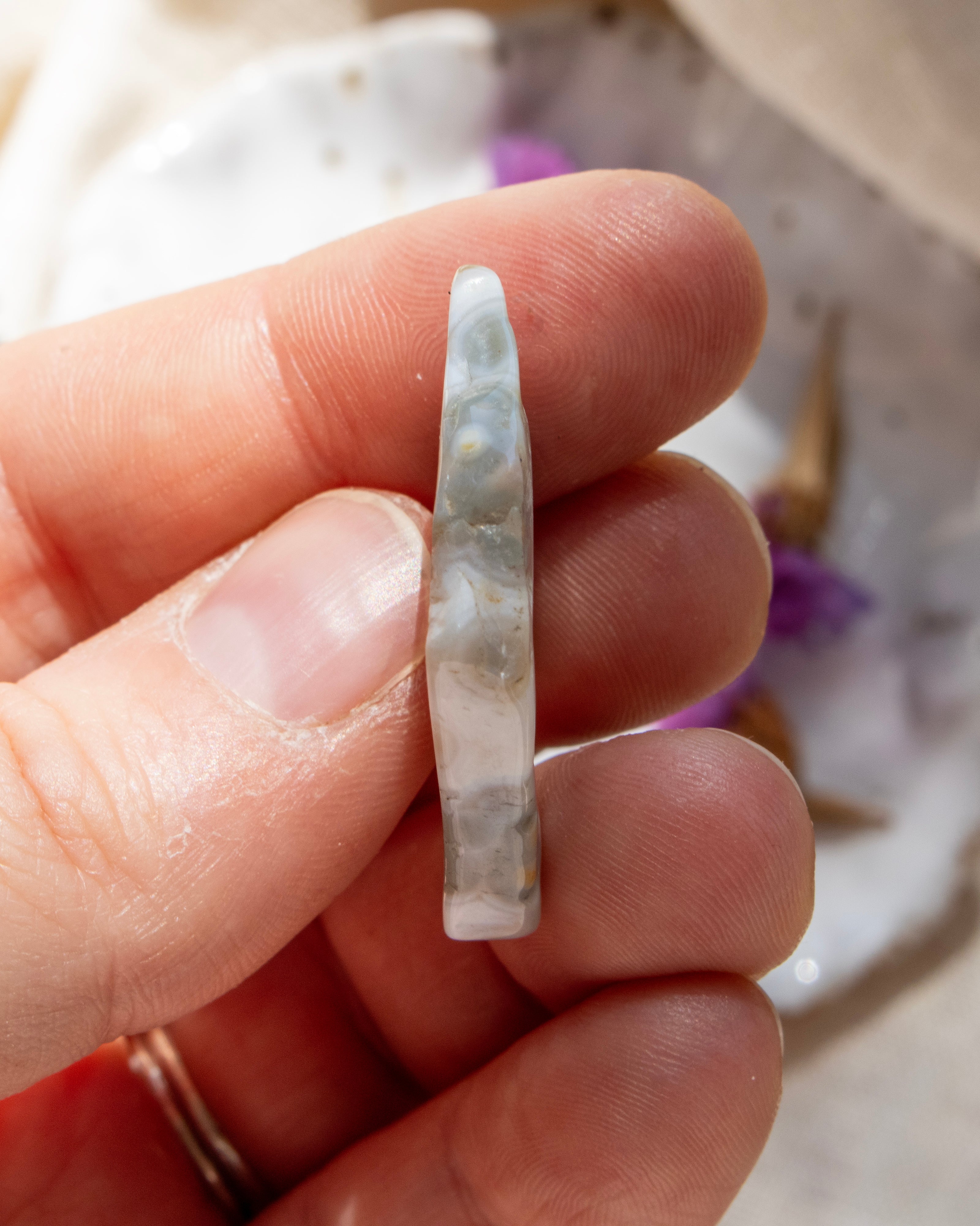 Hand holding a small, polished stone with a blurred background