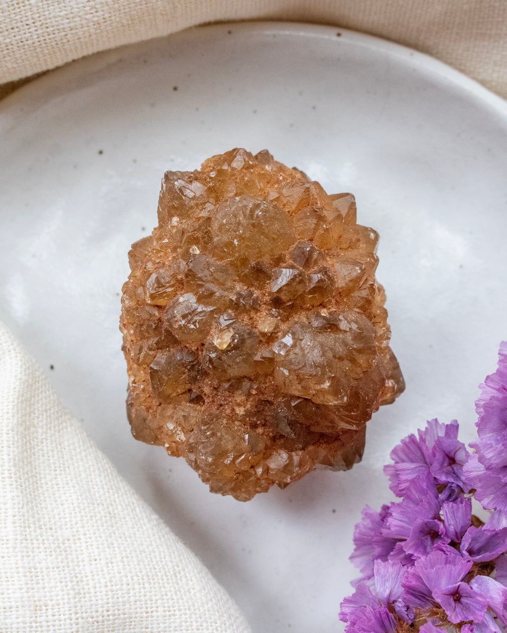 Crystal cluster on a white plate with purple flowers
