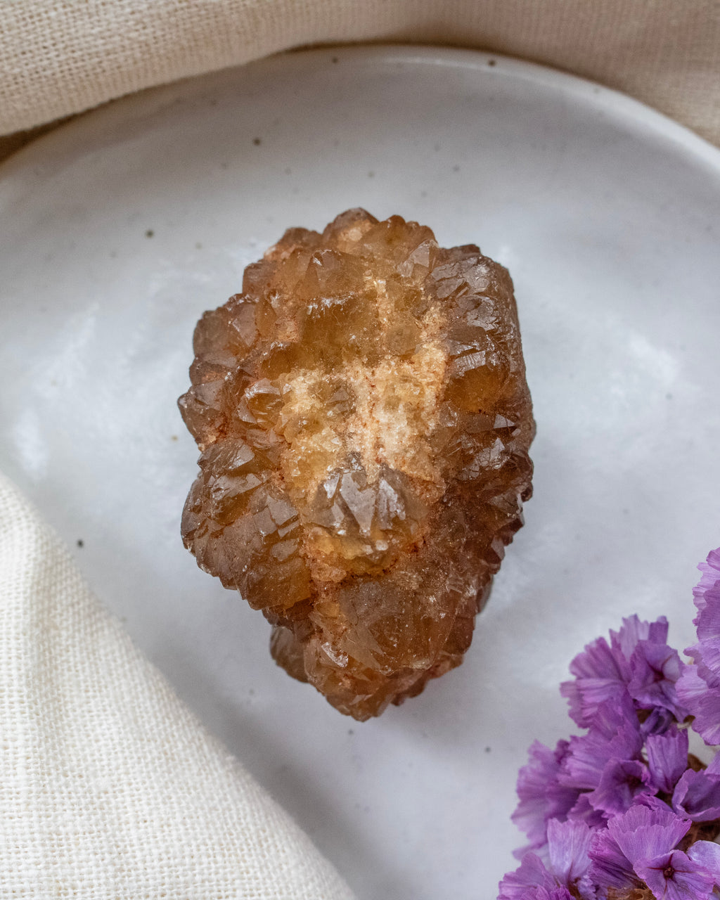 Brown crystal on a white plate with purple flowers