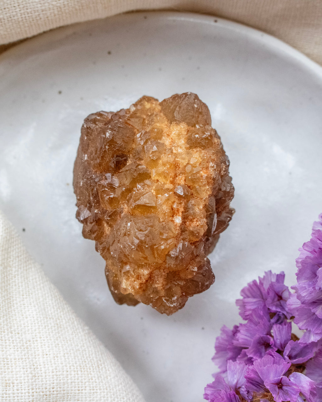 Brown crystal on a white plate with purple flowers