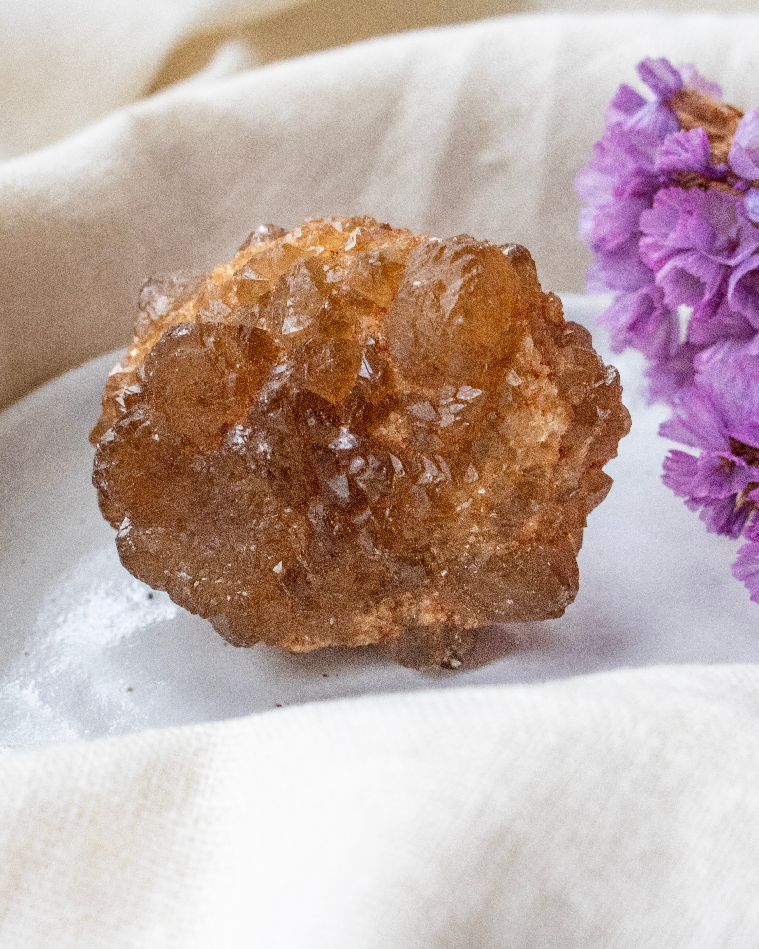 Brown crystal on a white surface with purple flowers