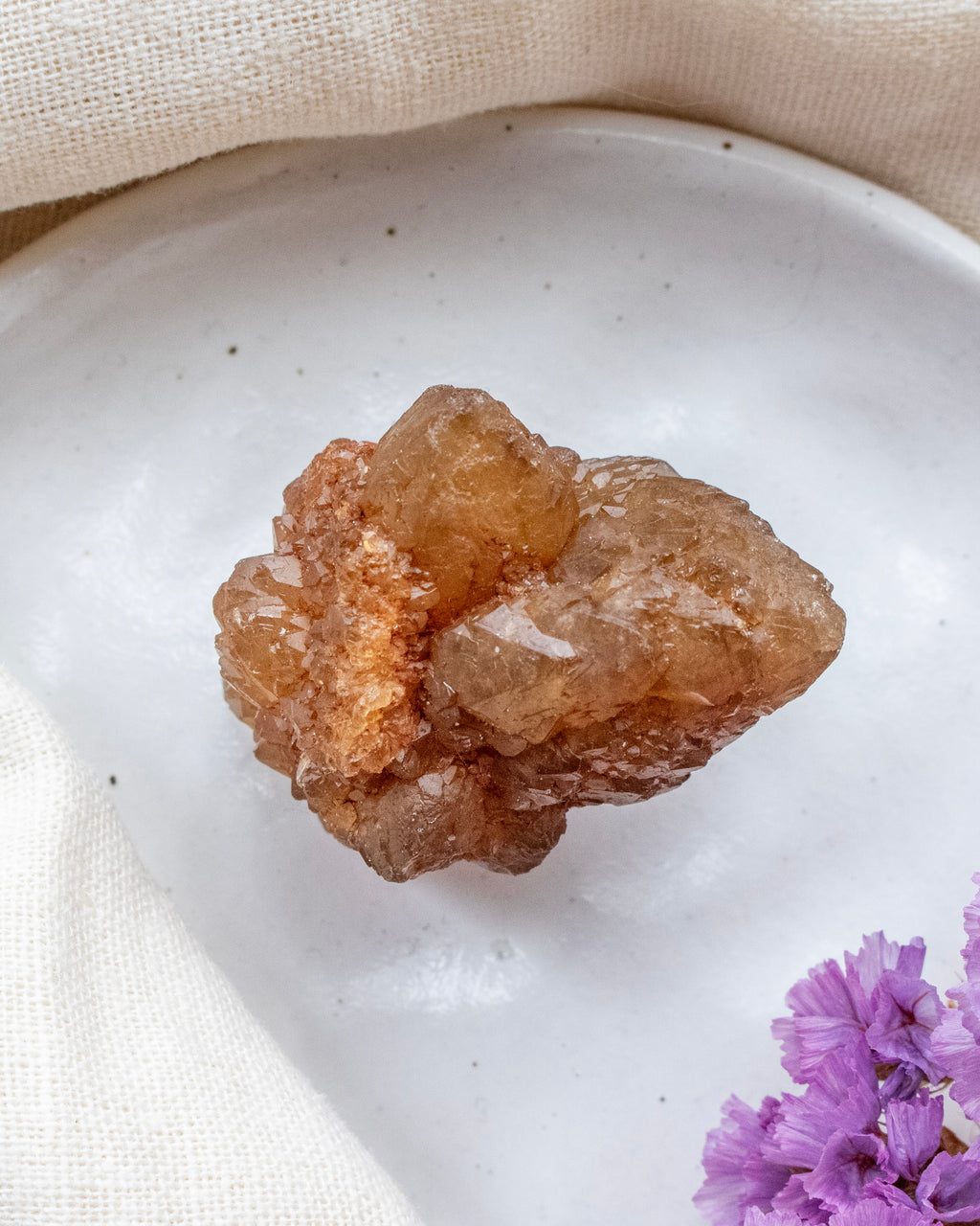Brown crystal on a white plate with purple flowers