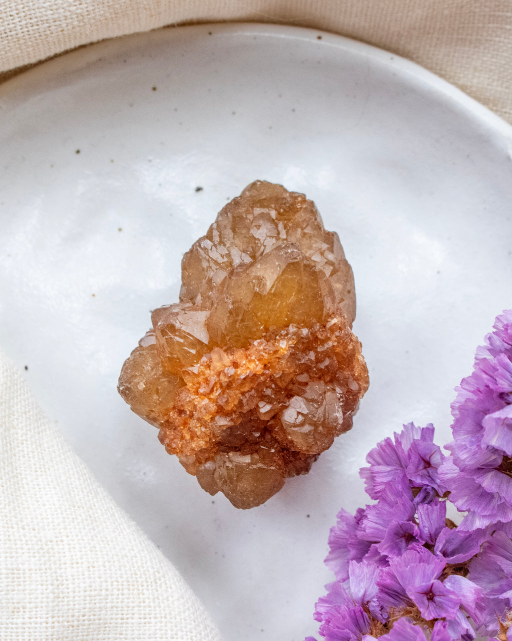 Brown crystal on a white plate with purple flowers