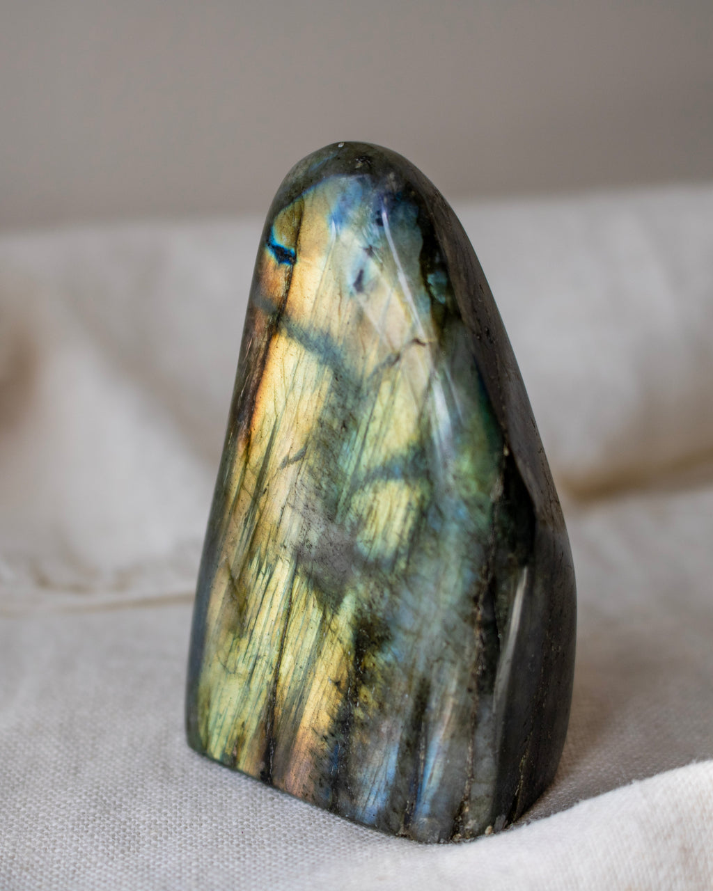 Labradorite stone with multicolored patterns on a beige fabric background