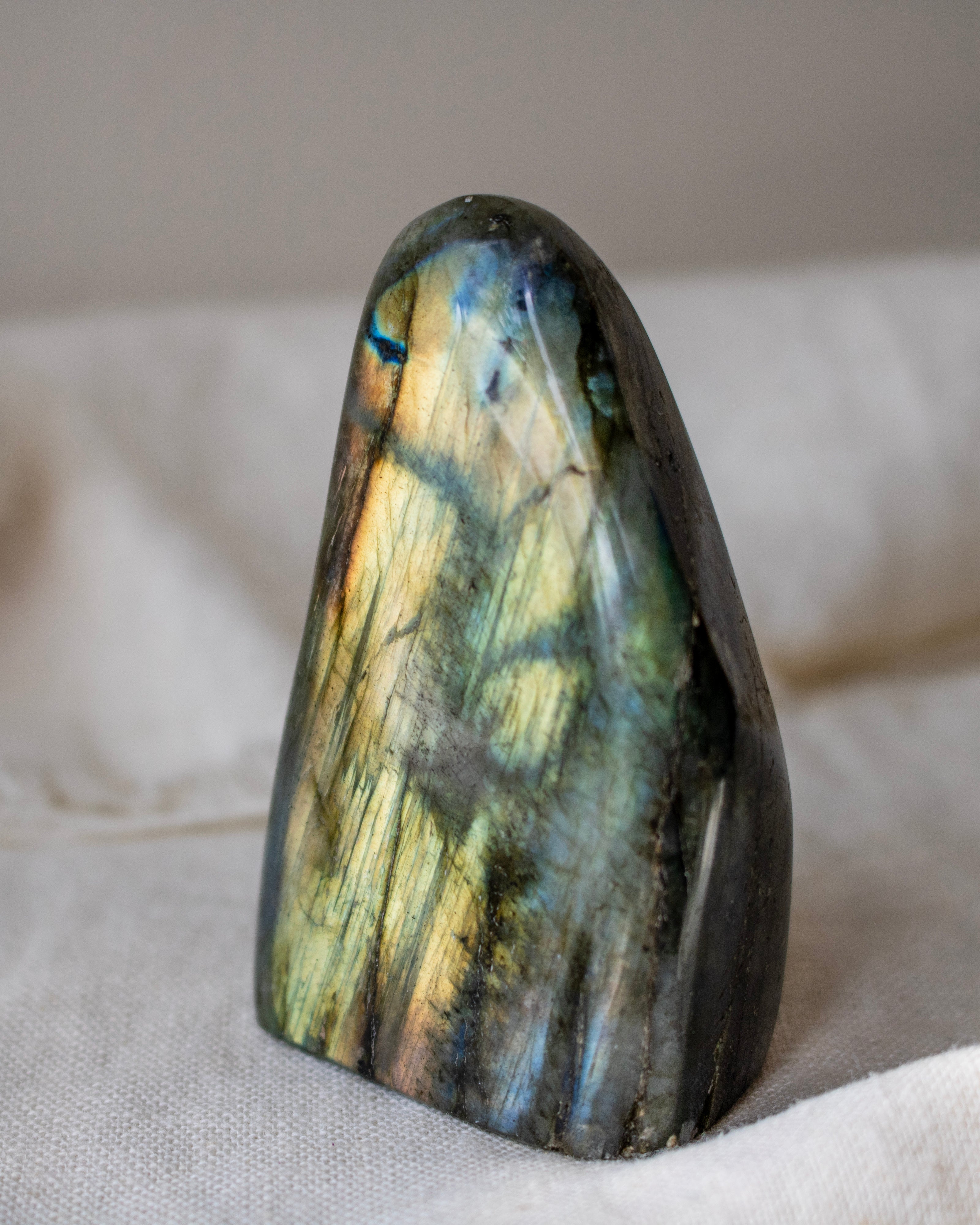 Labradorite stone with multicolored patterns on a beige fabric background