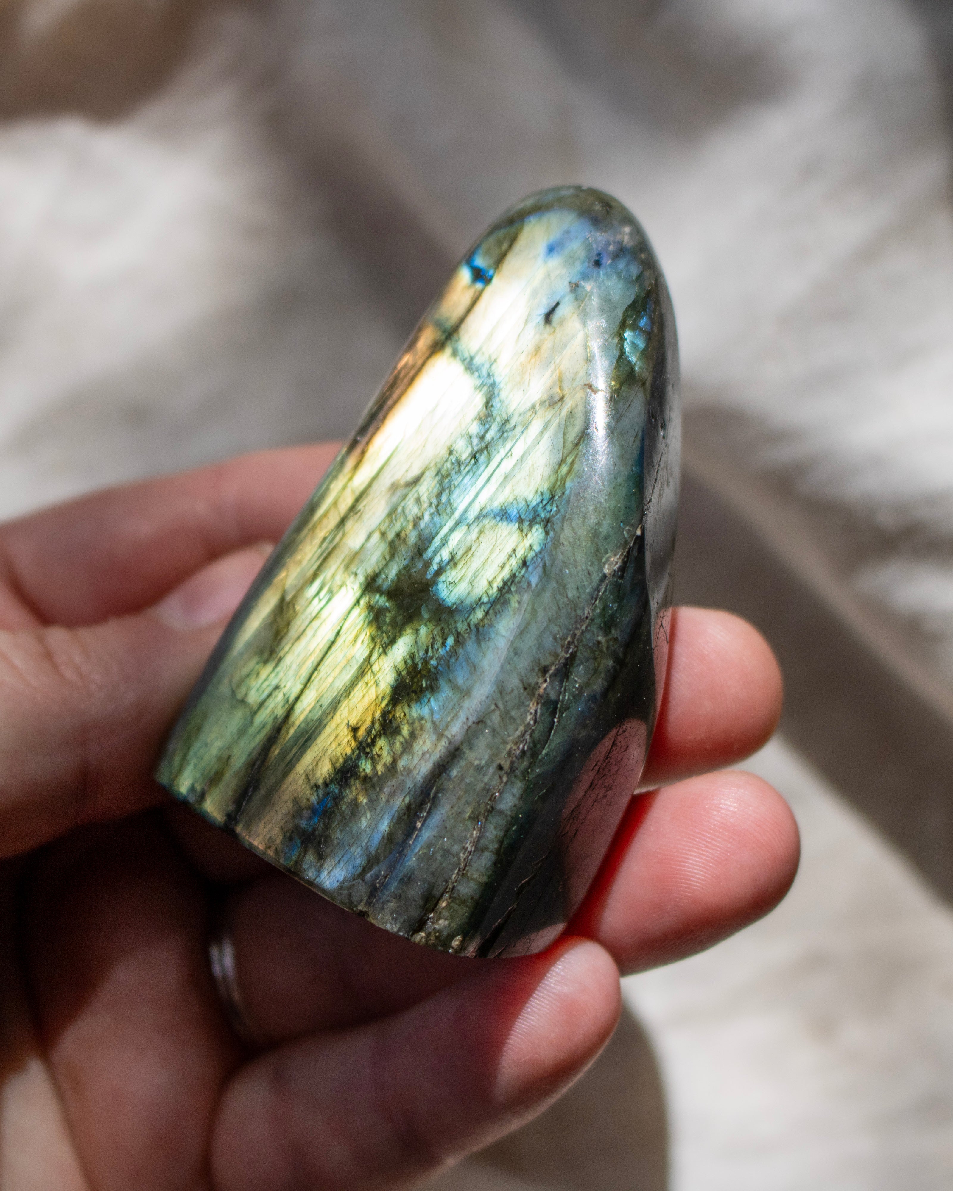 Hand holding a labradorite stone with a reflective surface