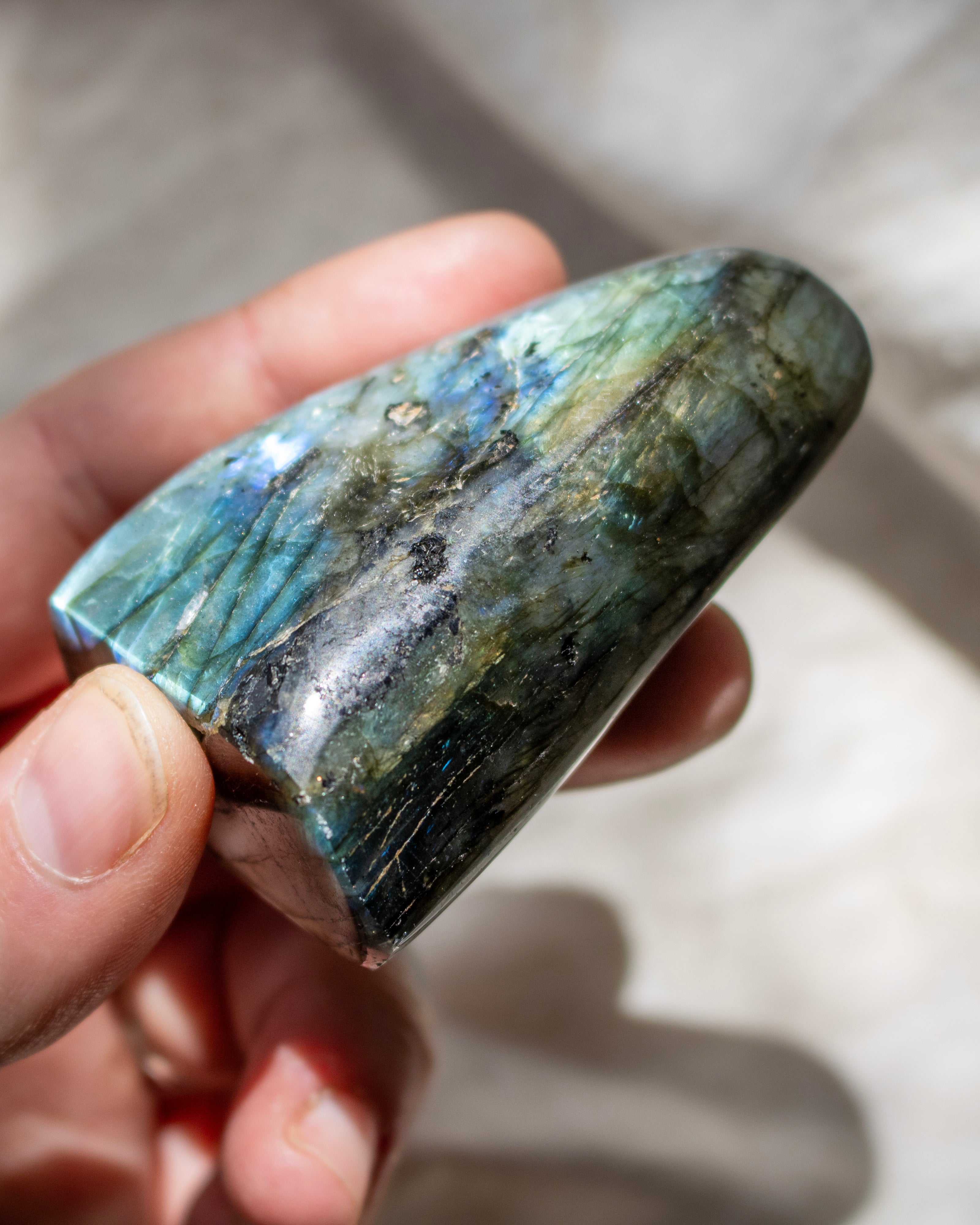 Hand holding a labradorite stone with a blurred background