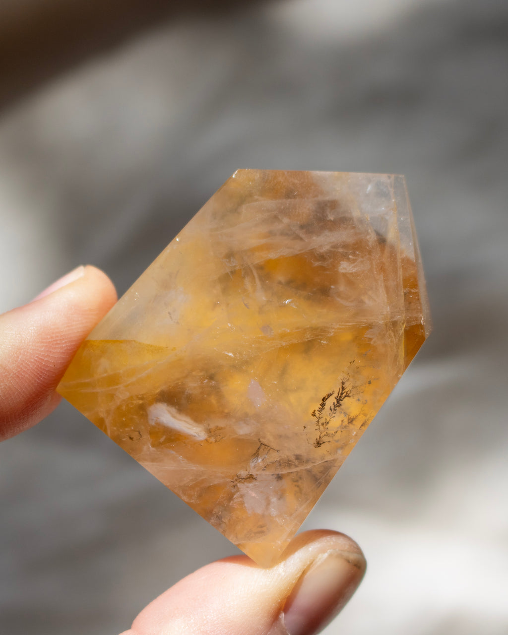 Clear crystal held by a hand against a blurred background