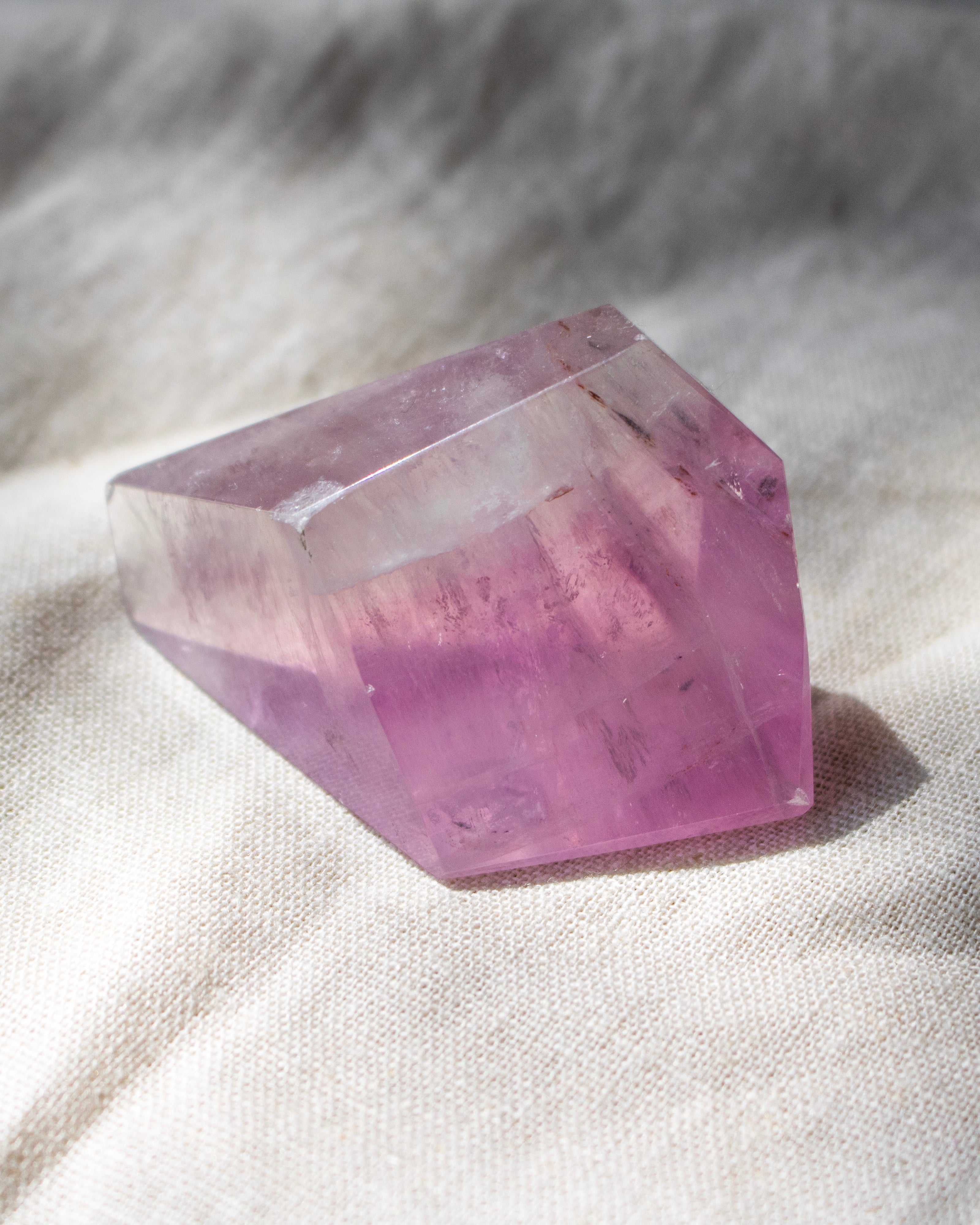 Crystal with purple and clear colors on a textured white surface