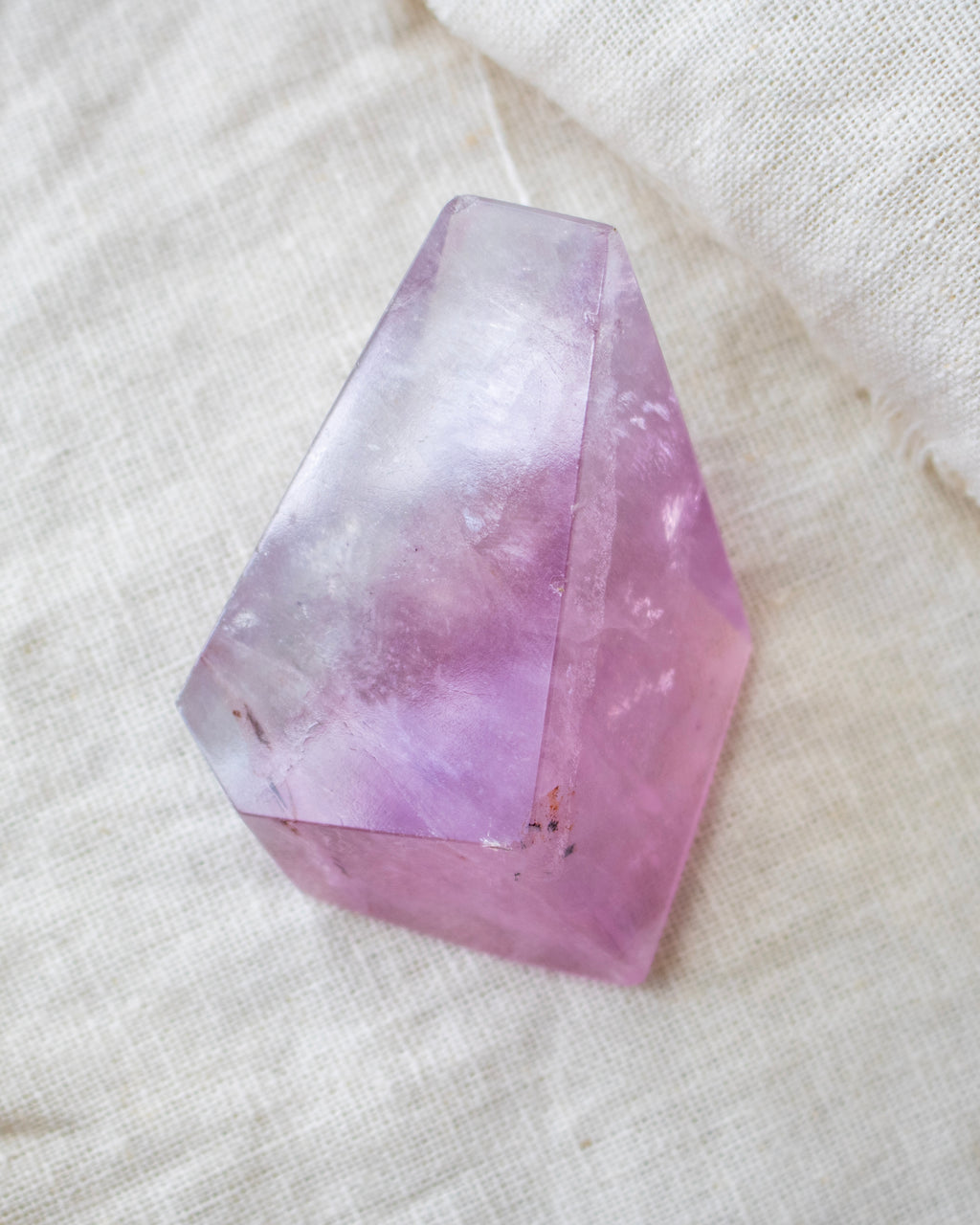 Faceted purple crystal on a textured white surface
