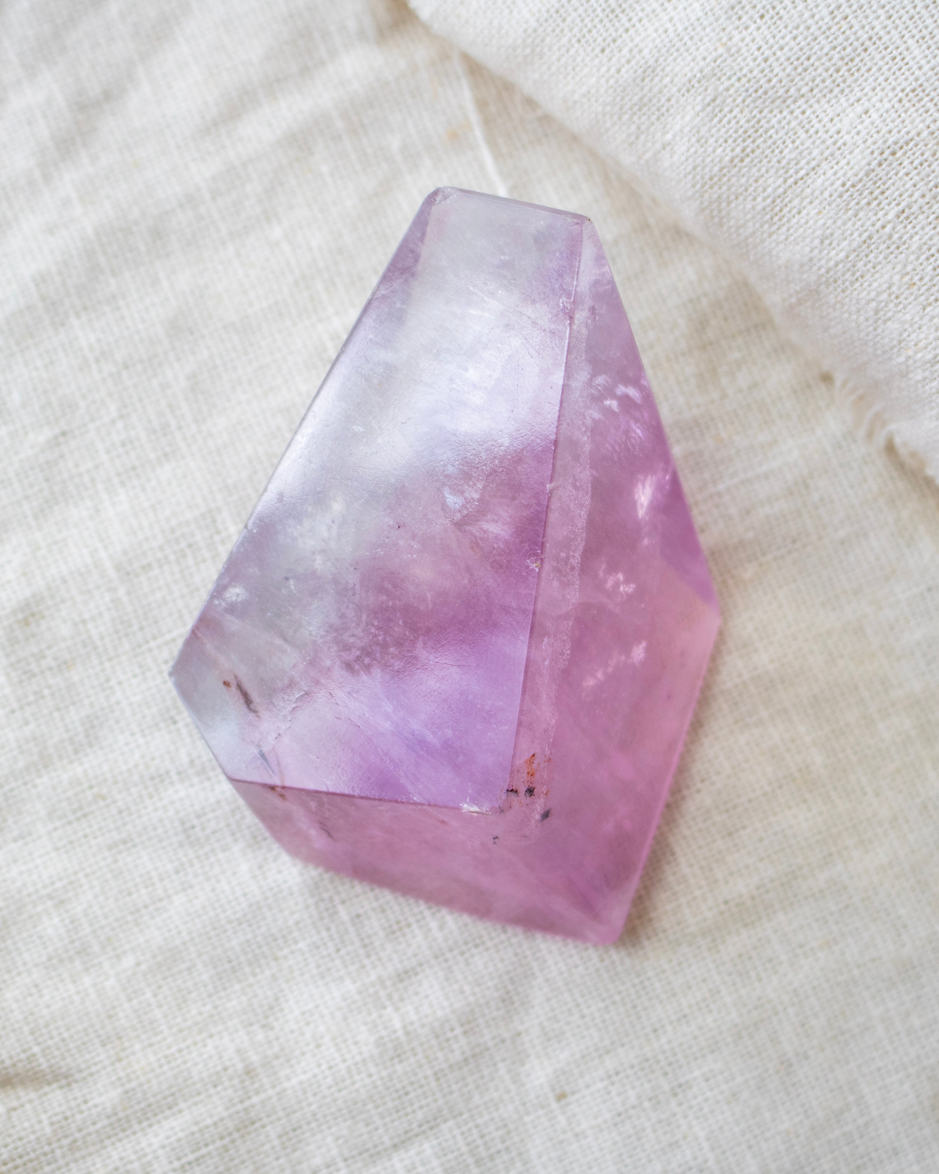 Faceted purple crystal on a textured white surface
