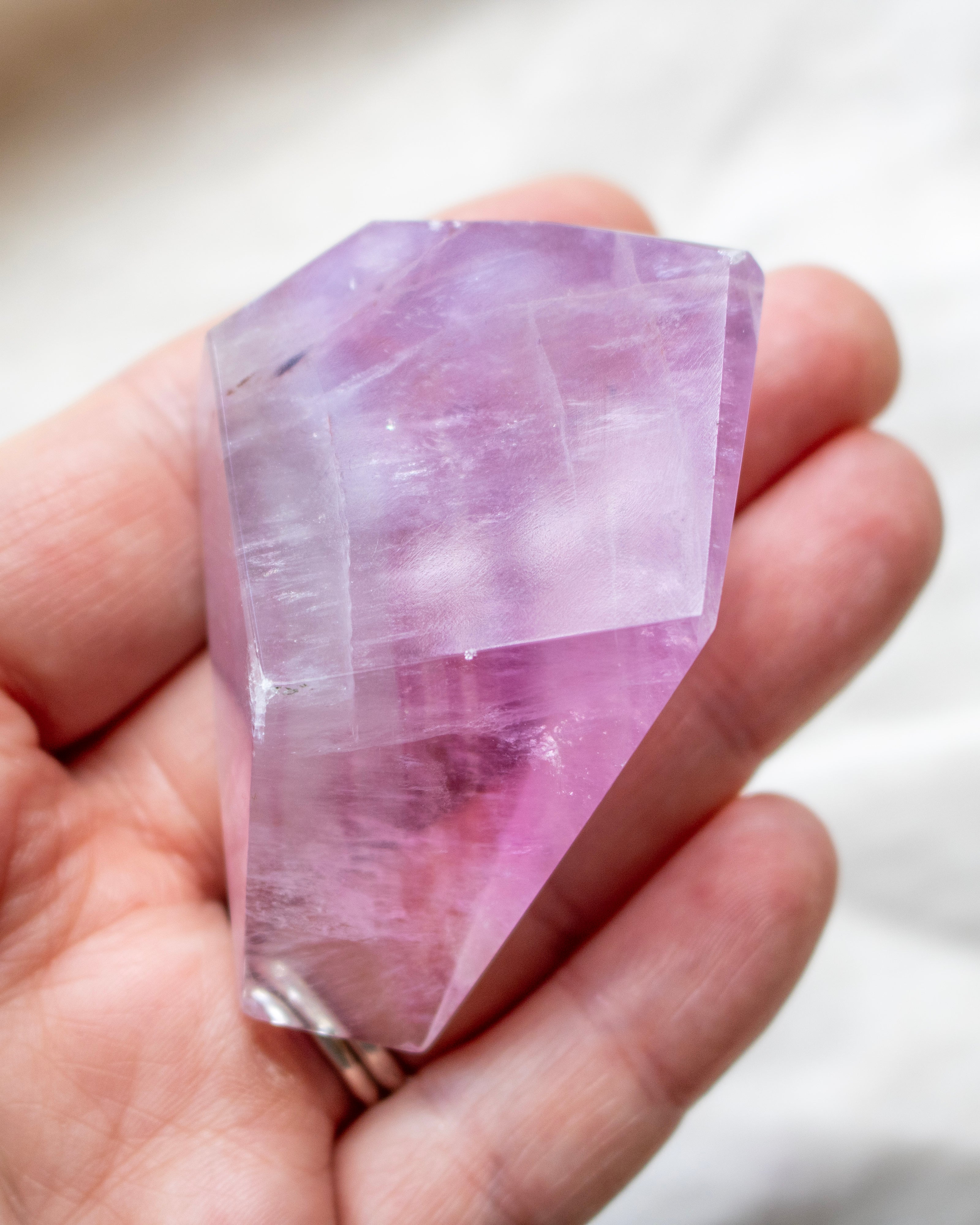 Hand holding a pink crystal against a blurred background